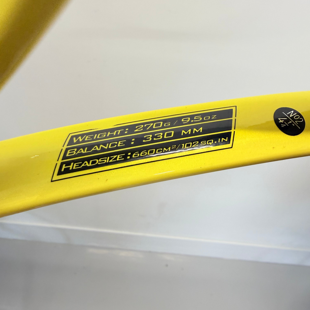 Specification label on Babolat Evoke 102 tennis racket showing weight, balance, and head size