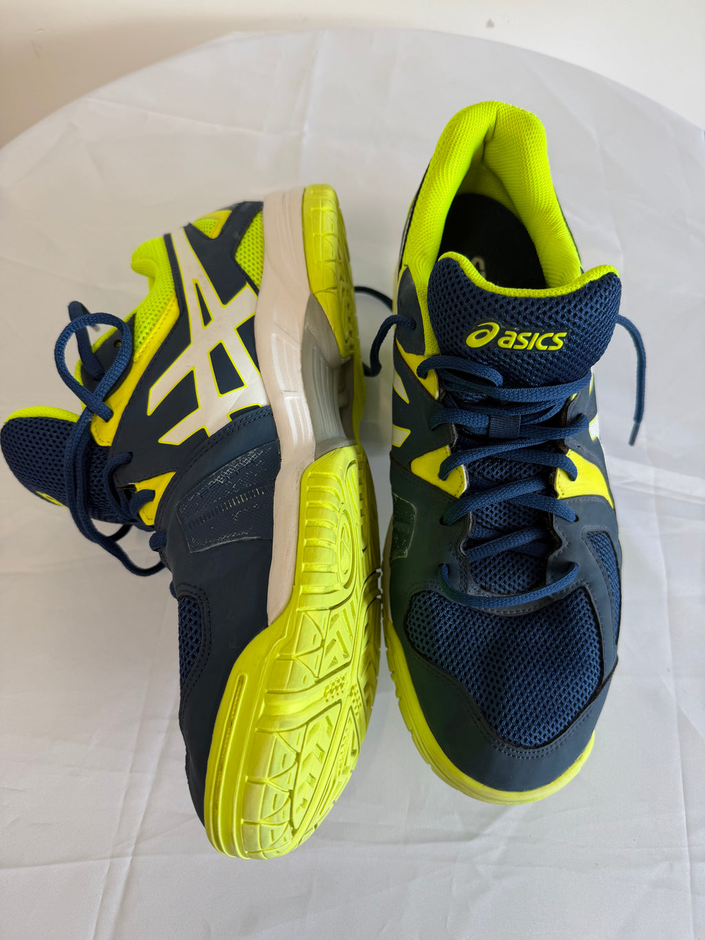 ASICS navy and yellow trainers side view showing logo and sole