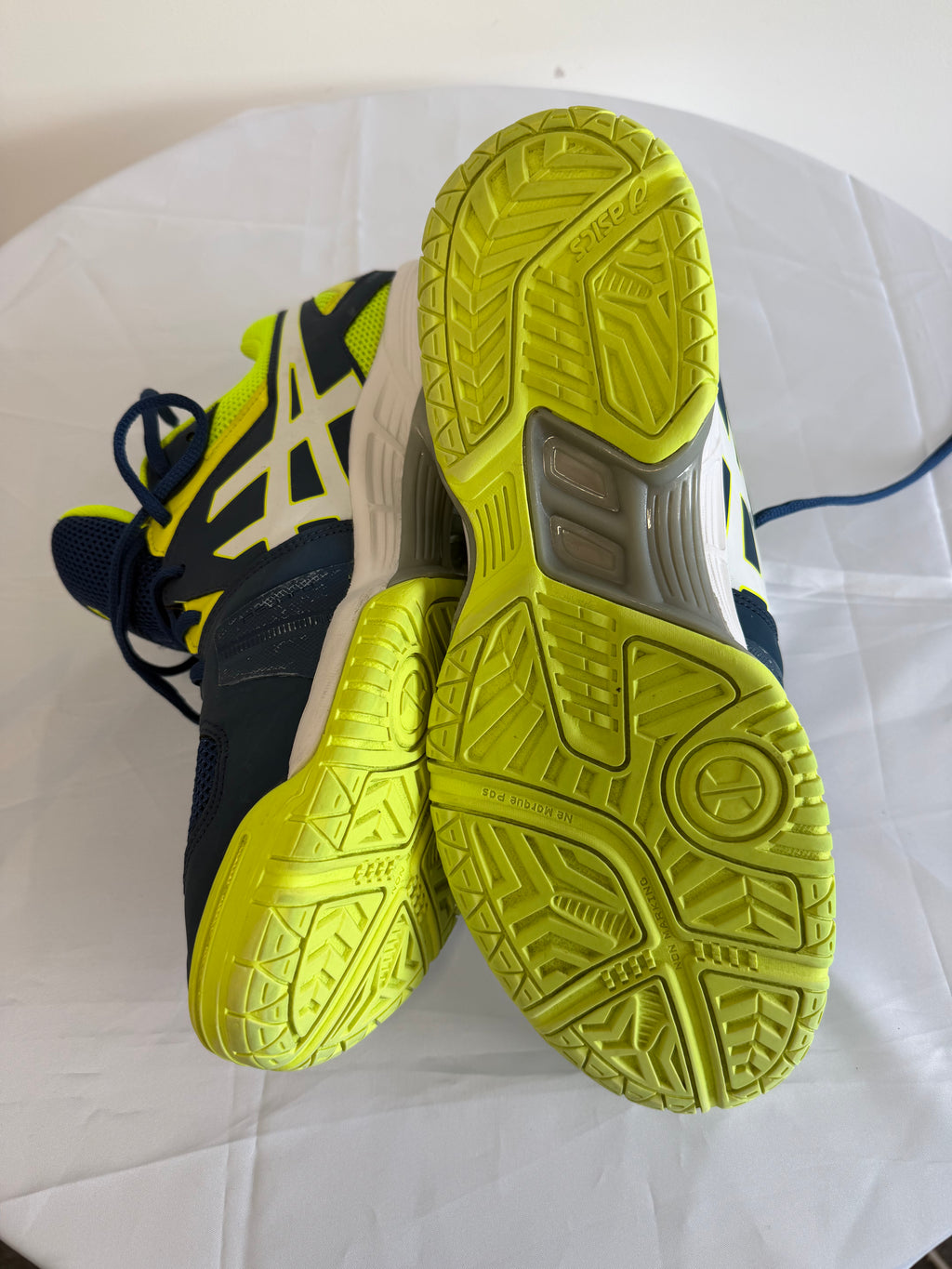 Soles of ASICS trainers with bright yellow rubber tread