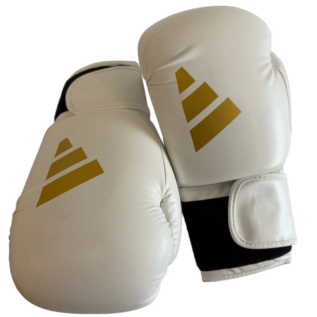 Pair of white adidas boxing gloves with gold logo and wrist straps