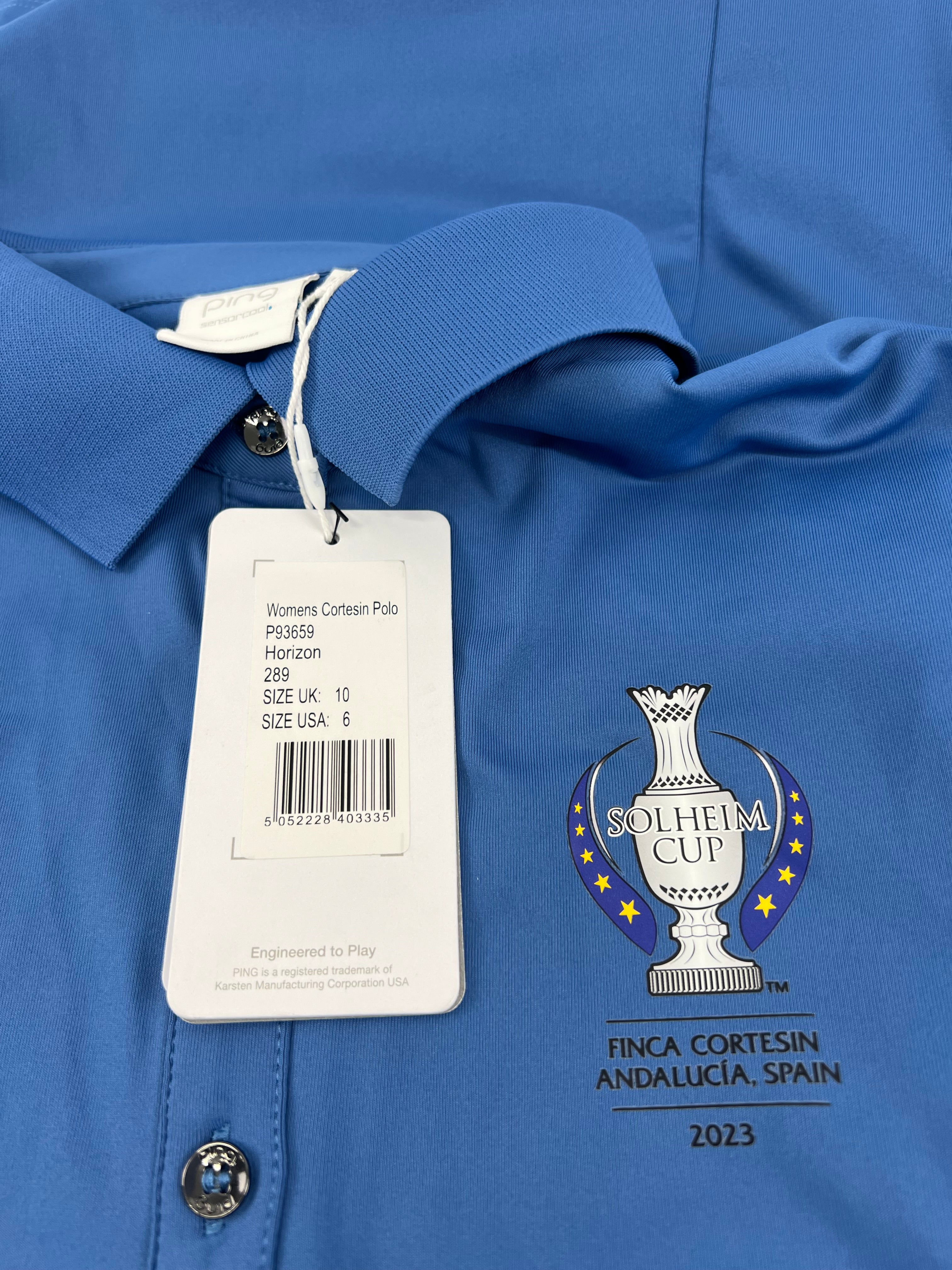 Close-up of Ping Solheim Cup 2023 embroidery and product tag detailing size and event information on horizon blue polo shirt