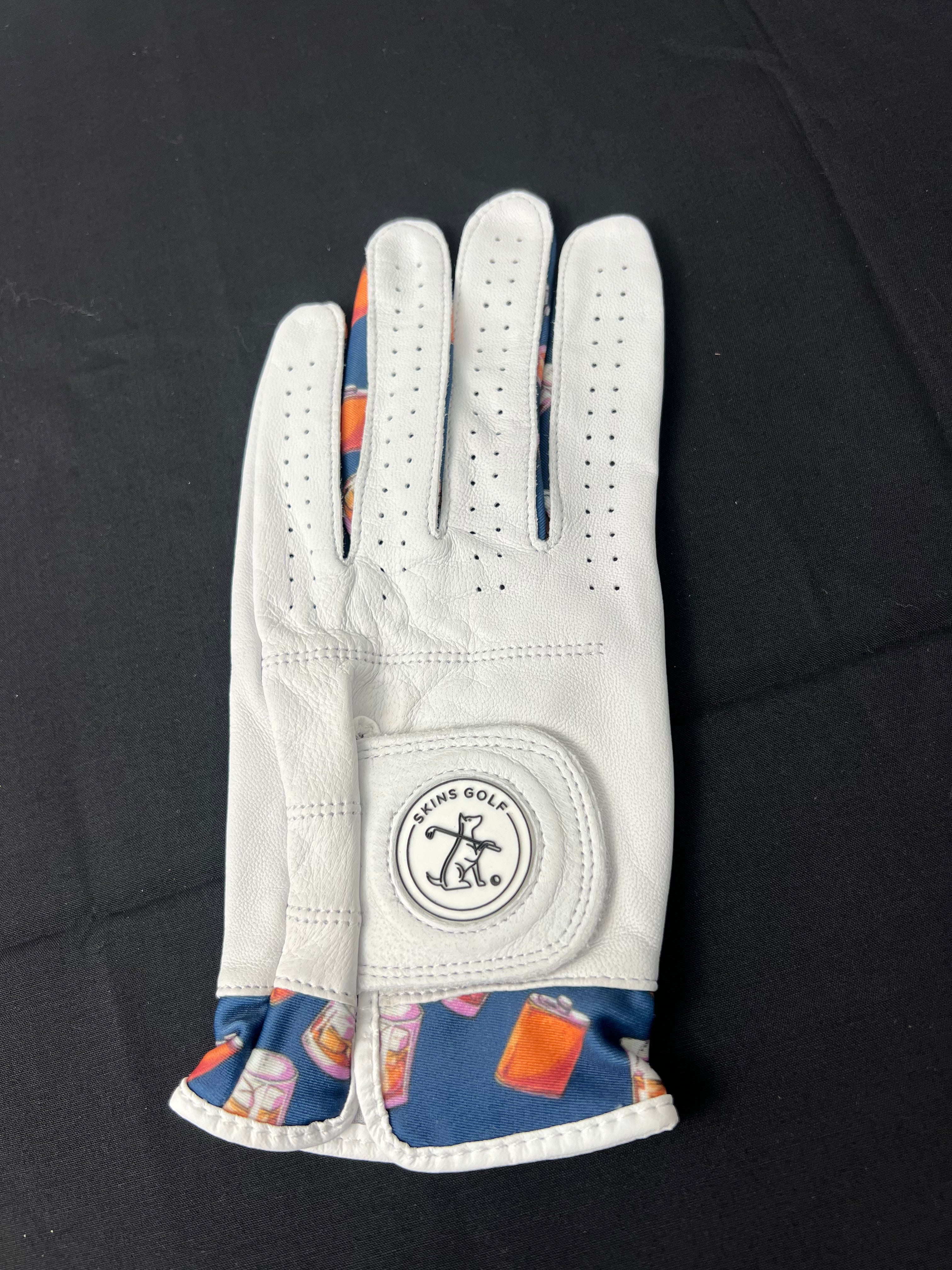 Women's white golf glove with whiskey motif cuff, left hand, laid flat on black background