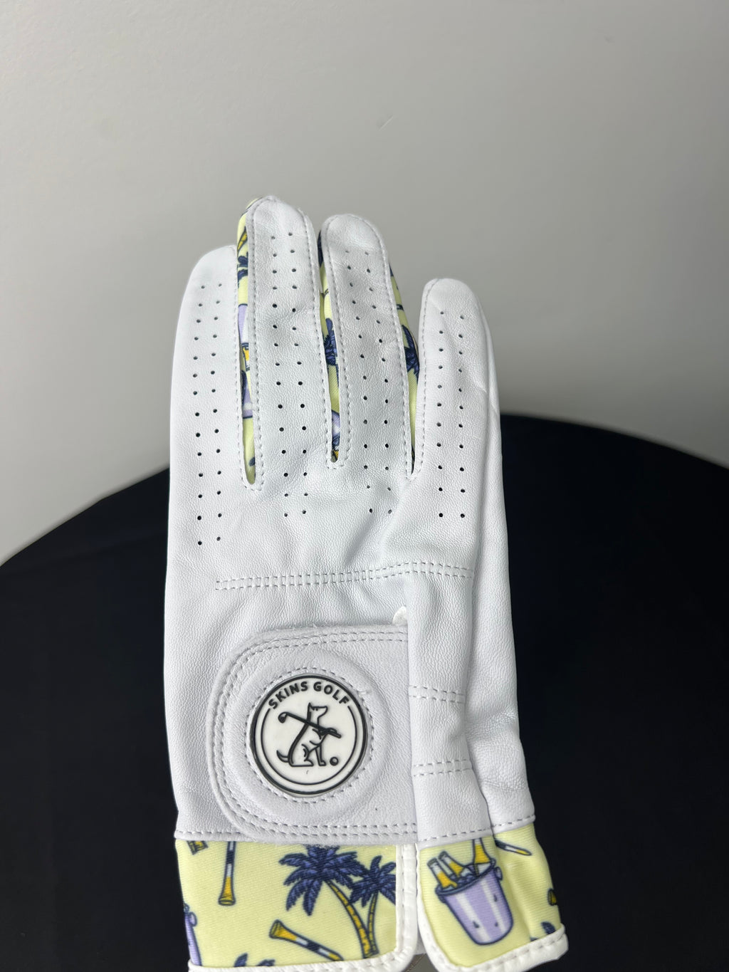 Women's right hand golf glove with palm tree and golf clubs motif at cuff, shown palm up.