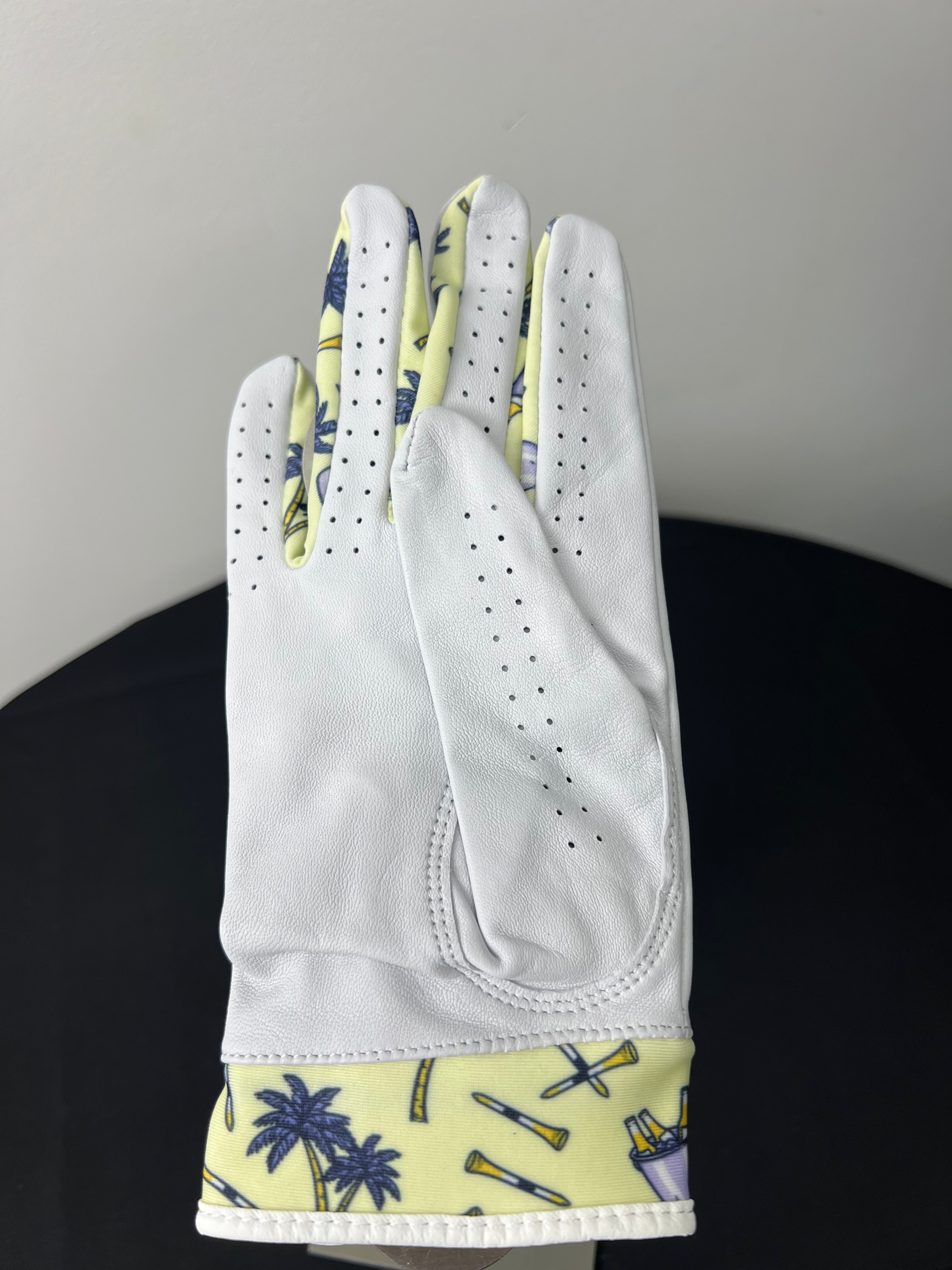 Women's right hand golf glove with tropical palm tree motif at cuff, shown palm down.