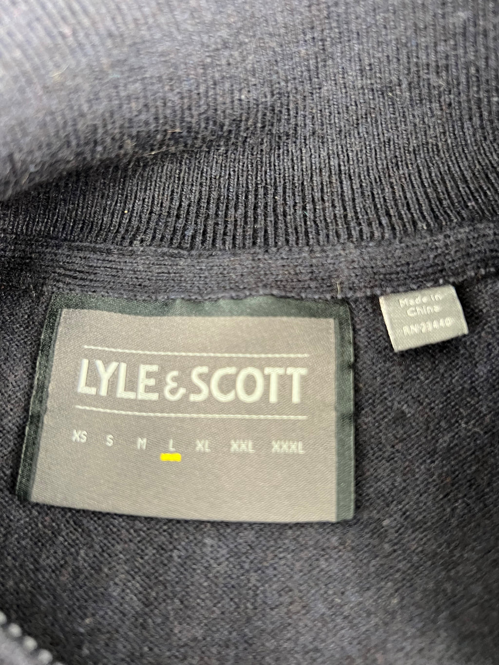 Close up of Lyle and Scott label and size tag inside the navy sleeveless pullover