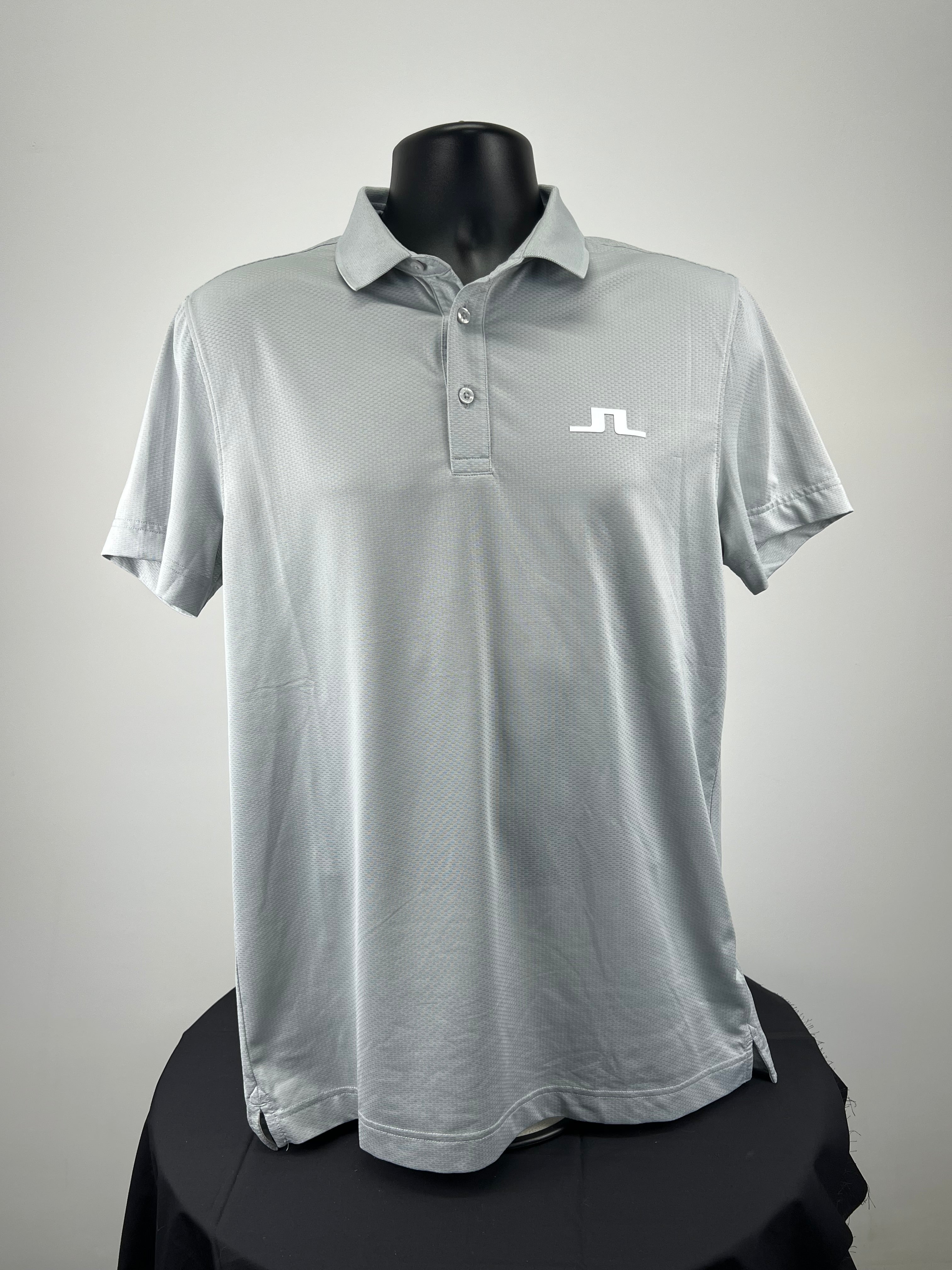 Front view of men's J.Lindeberg grey polo shirt on black mannequin showing logo on chest