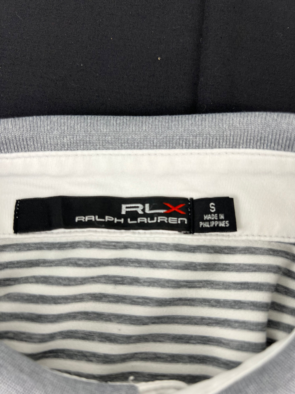 Close-up detail of Ralph Lauren RLX size S label inside the grey and white striped polo shirt