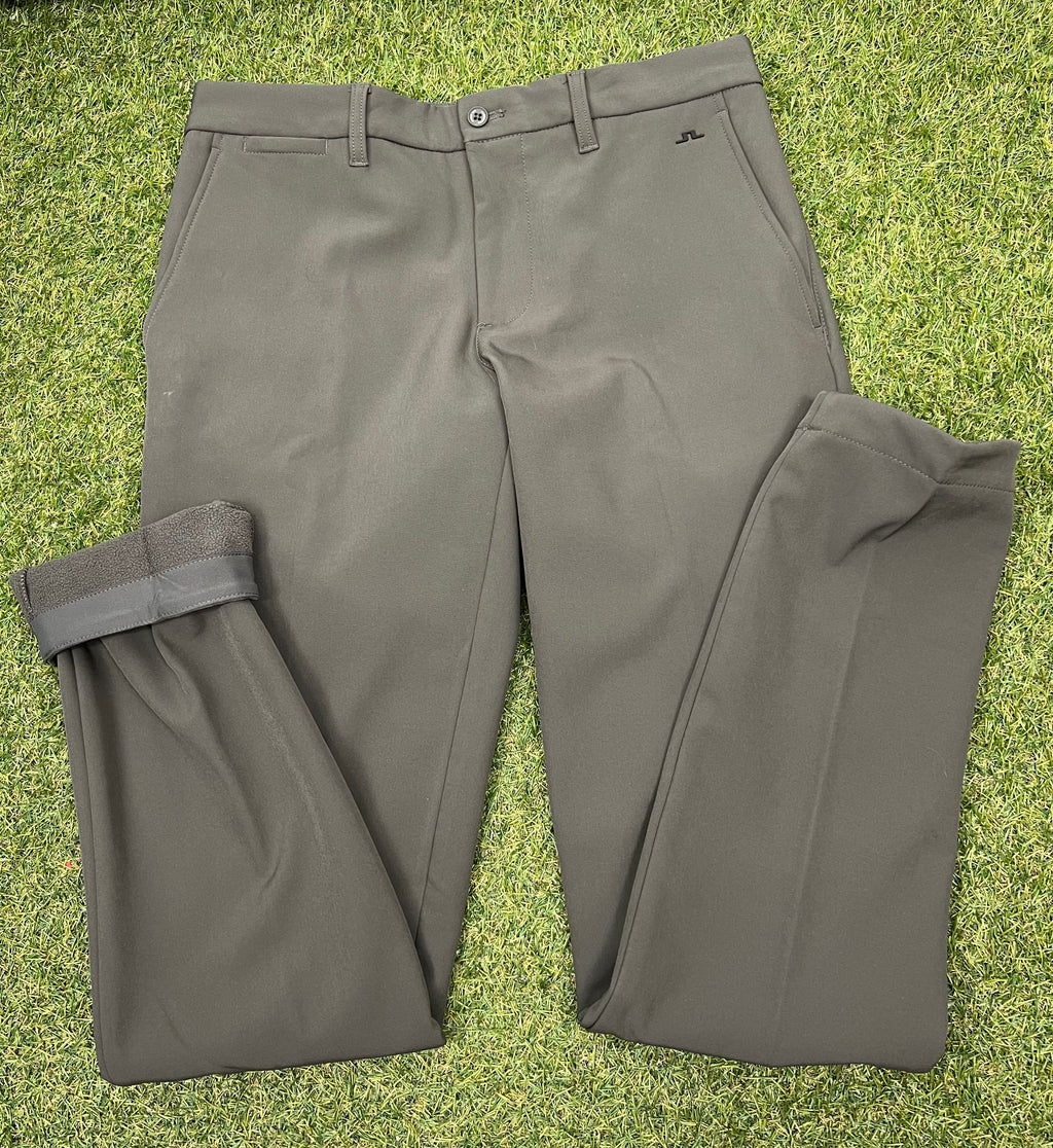 Front view of men’s J.Lindeberg Ellott khaki bonded fleece trousers laid flat on grass showing button and pockets