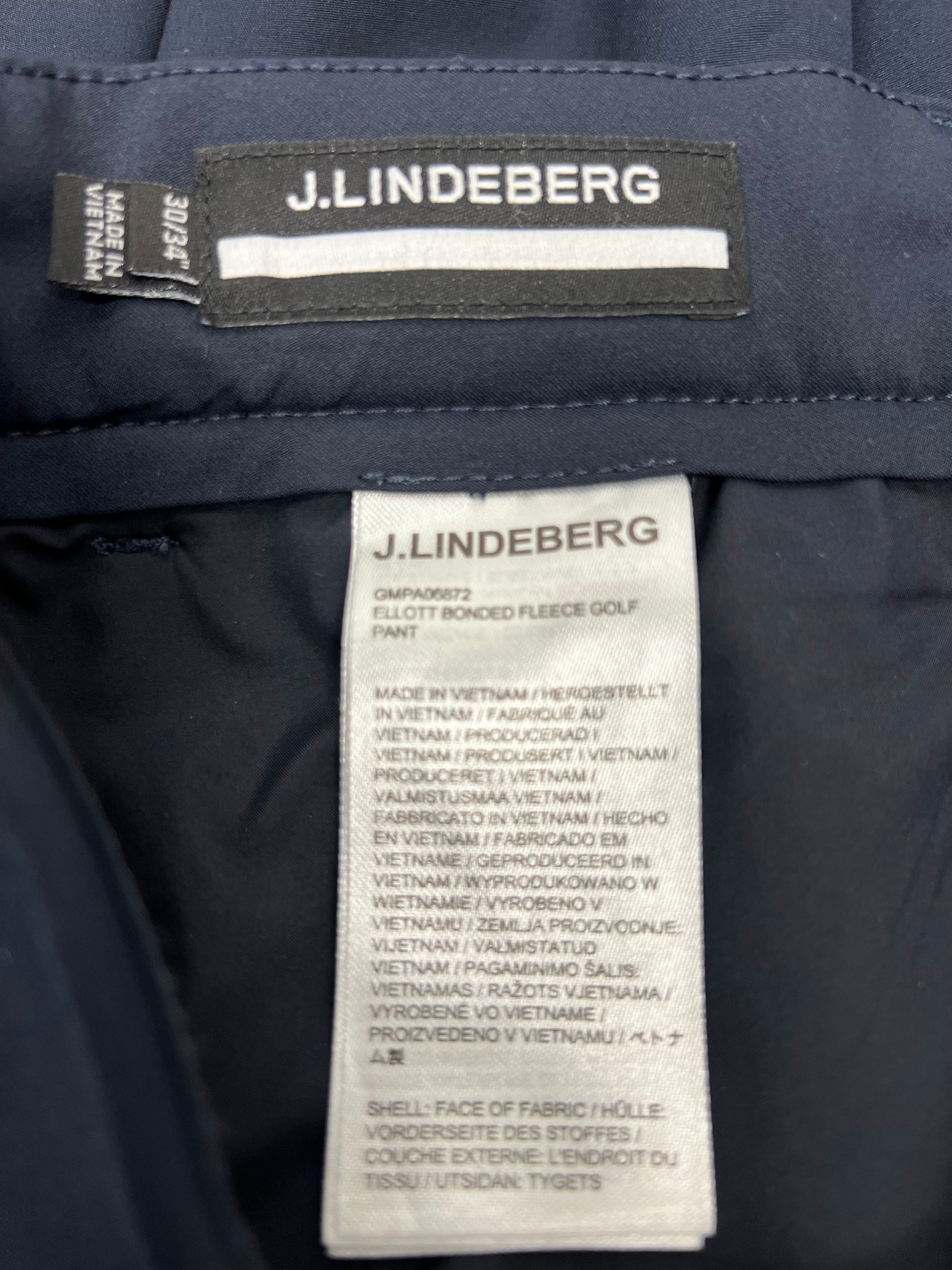 Close-up of J.Lindeberg brand label and care tag inside the navy bonded fleece trousers