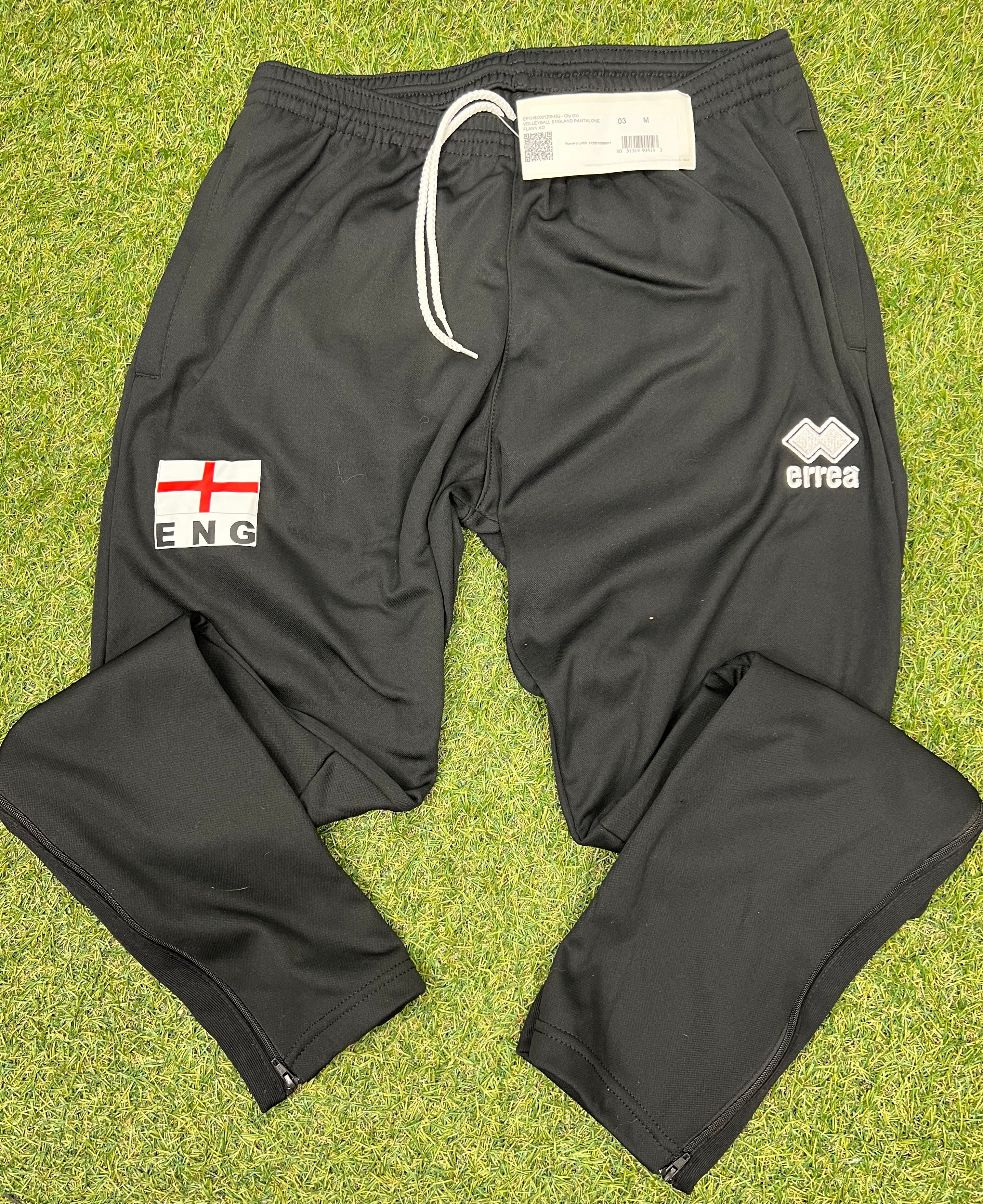 Front view of black volleyball tracksuit bottoms with England flag and Errea logos on grass