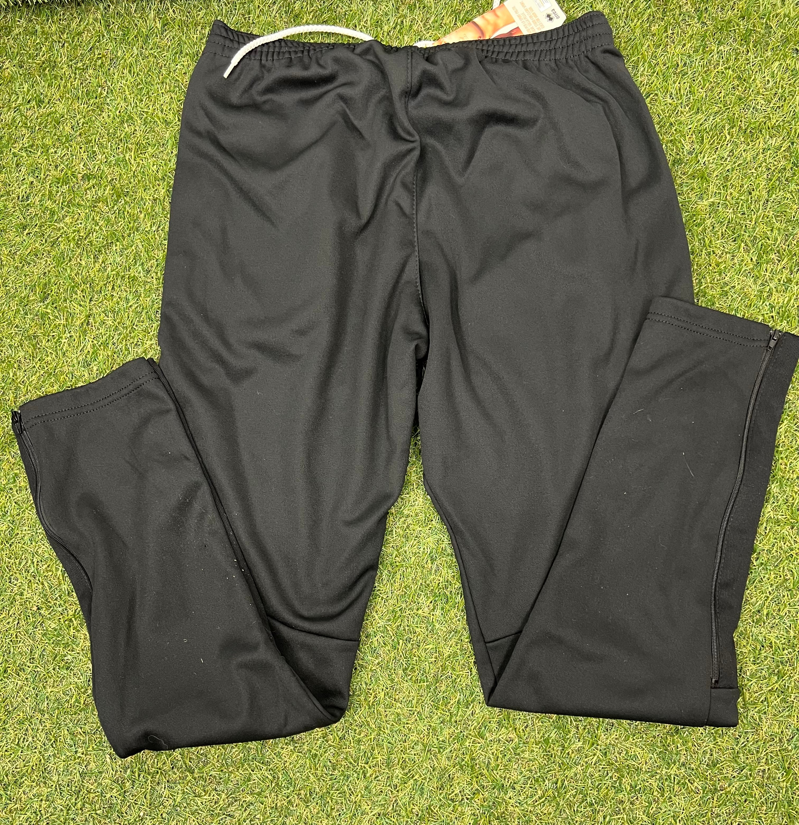 Back view of black volleyball tracksuit bottoms showing smooth plain fabric with zippered ankle cuffs
