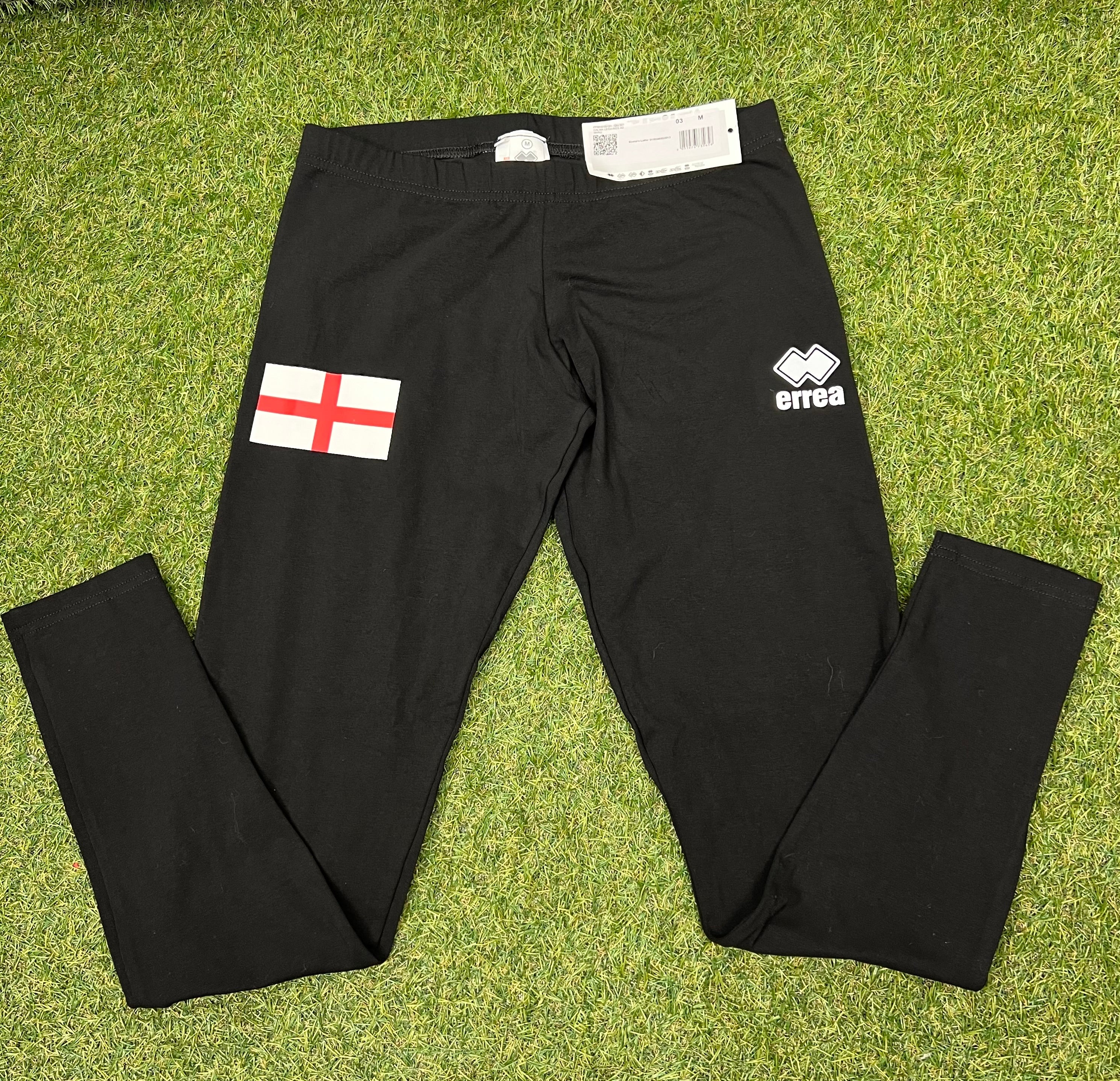 Front view of black women's leggings with England flag on left thigh and Errea logo on right thigh laid flat on grass
