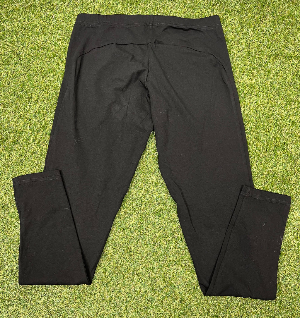 Back view of plain black women's leggings laid flat on grass