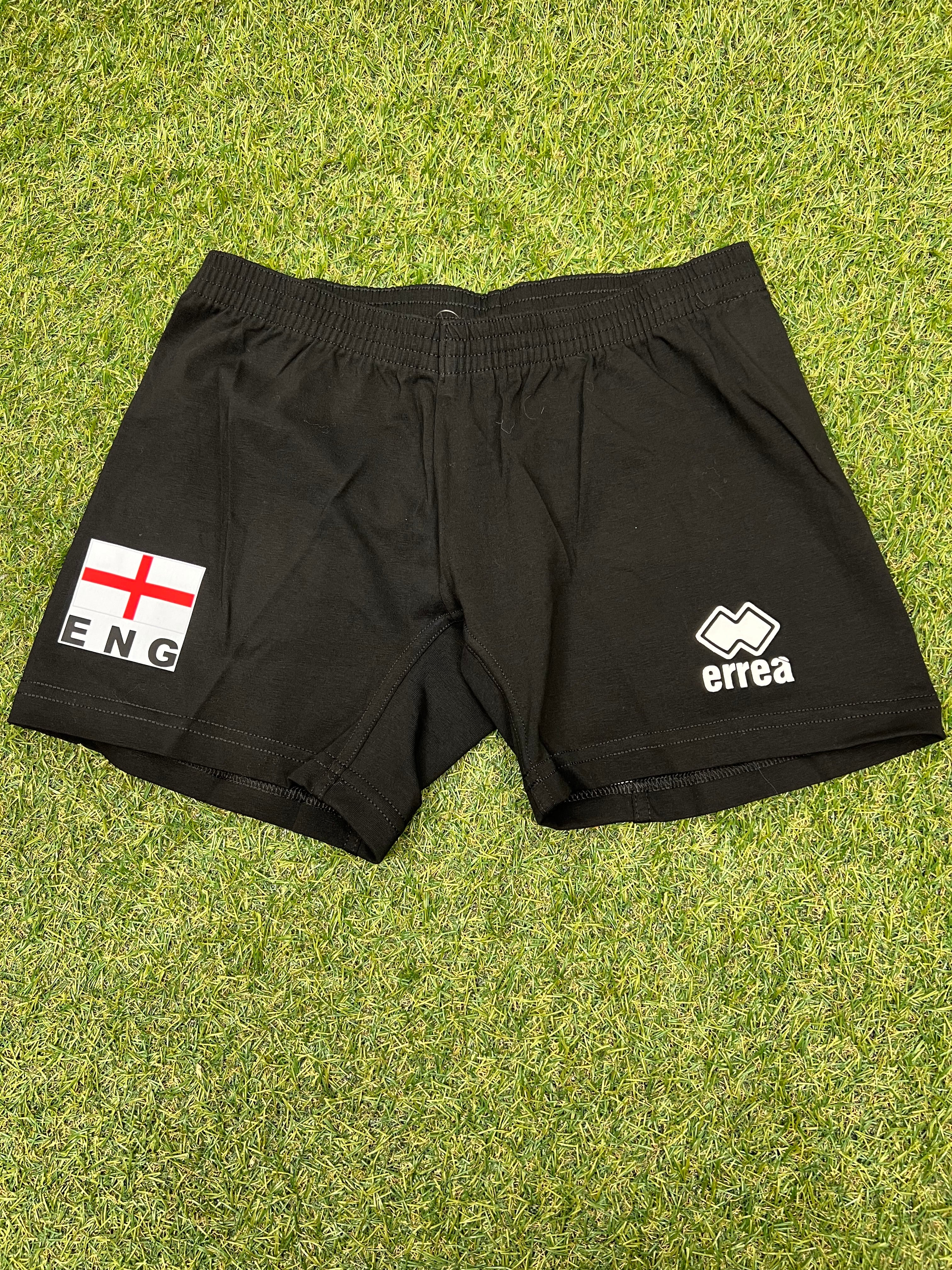 Front view of black Women's volleyball shorts with England flag and Errea logo on grass background
