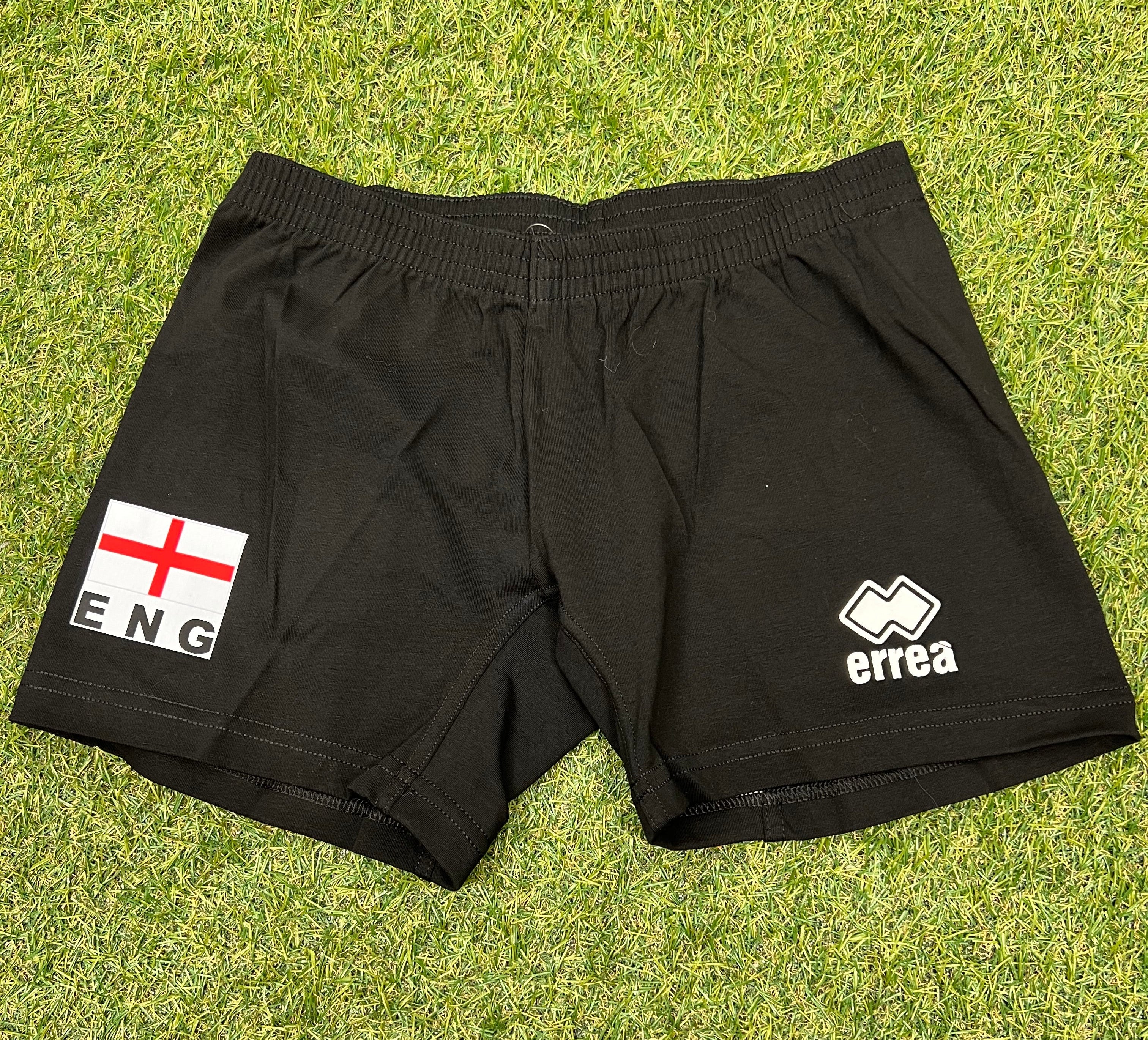 Front view of women’s volleyball shorts in black with England flag and Erreà logo on green grass