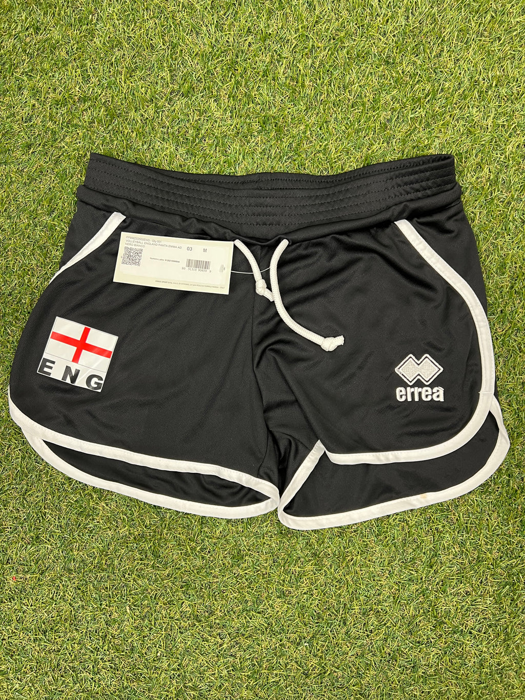 Front view of black women’s volleyball shorts with England flag patch and Erreà logo on grass