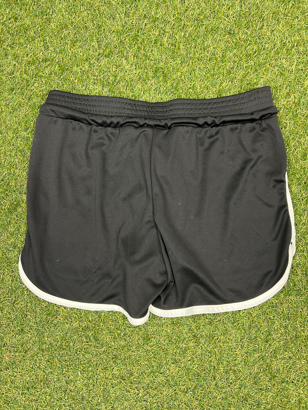 Reverse view of black women’s volleyball shorts showing elastic waistband and white trim