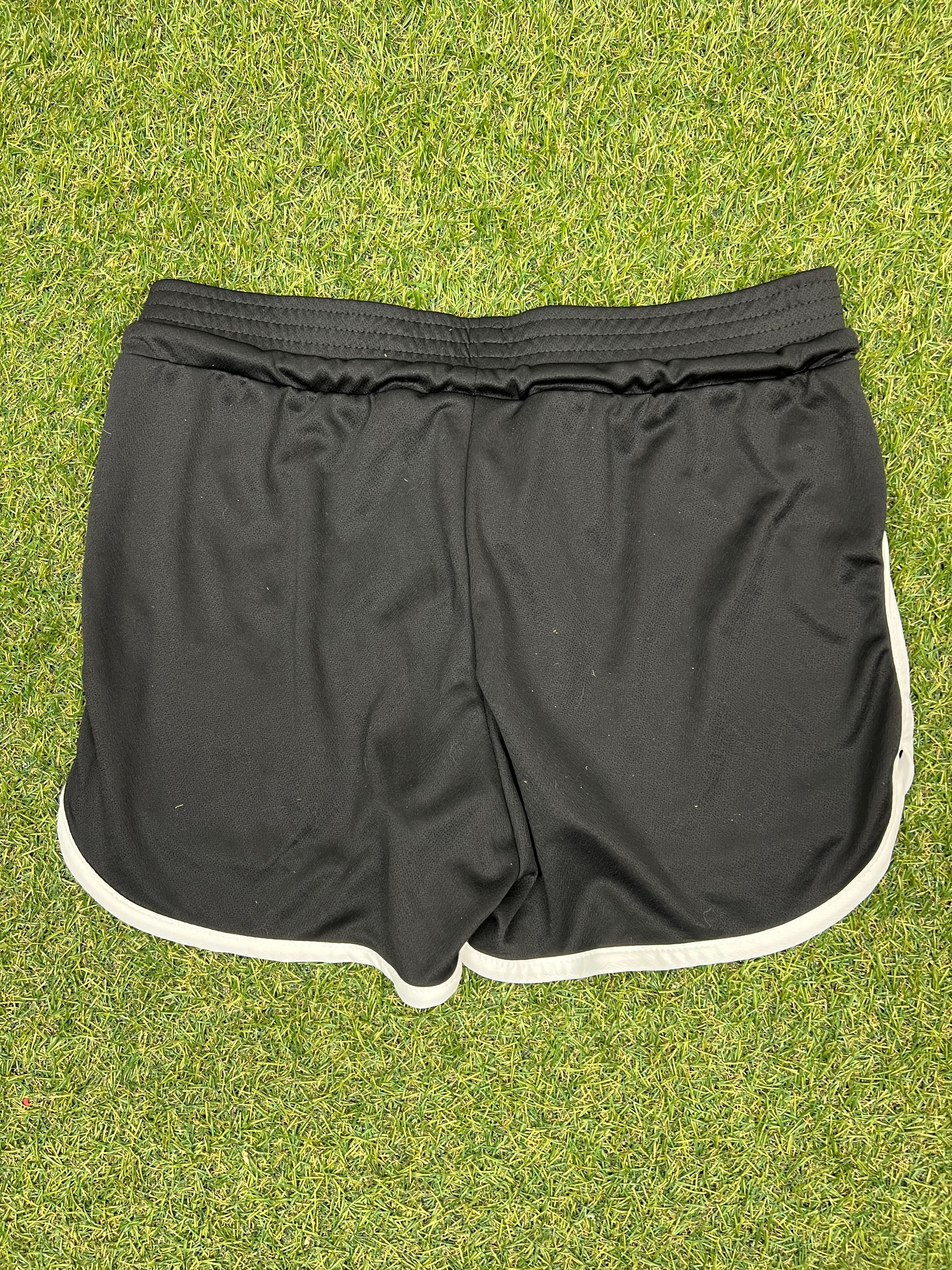 Reverse view of black women’s volleyball shorts showing elastic waistband and white trim