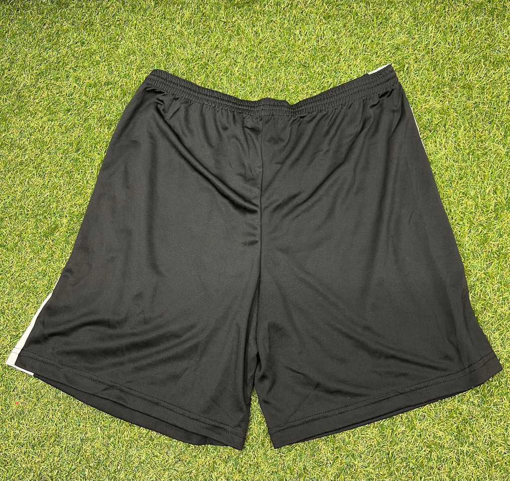 Back view of black men’s volleyball shorts with white side panels on grass background