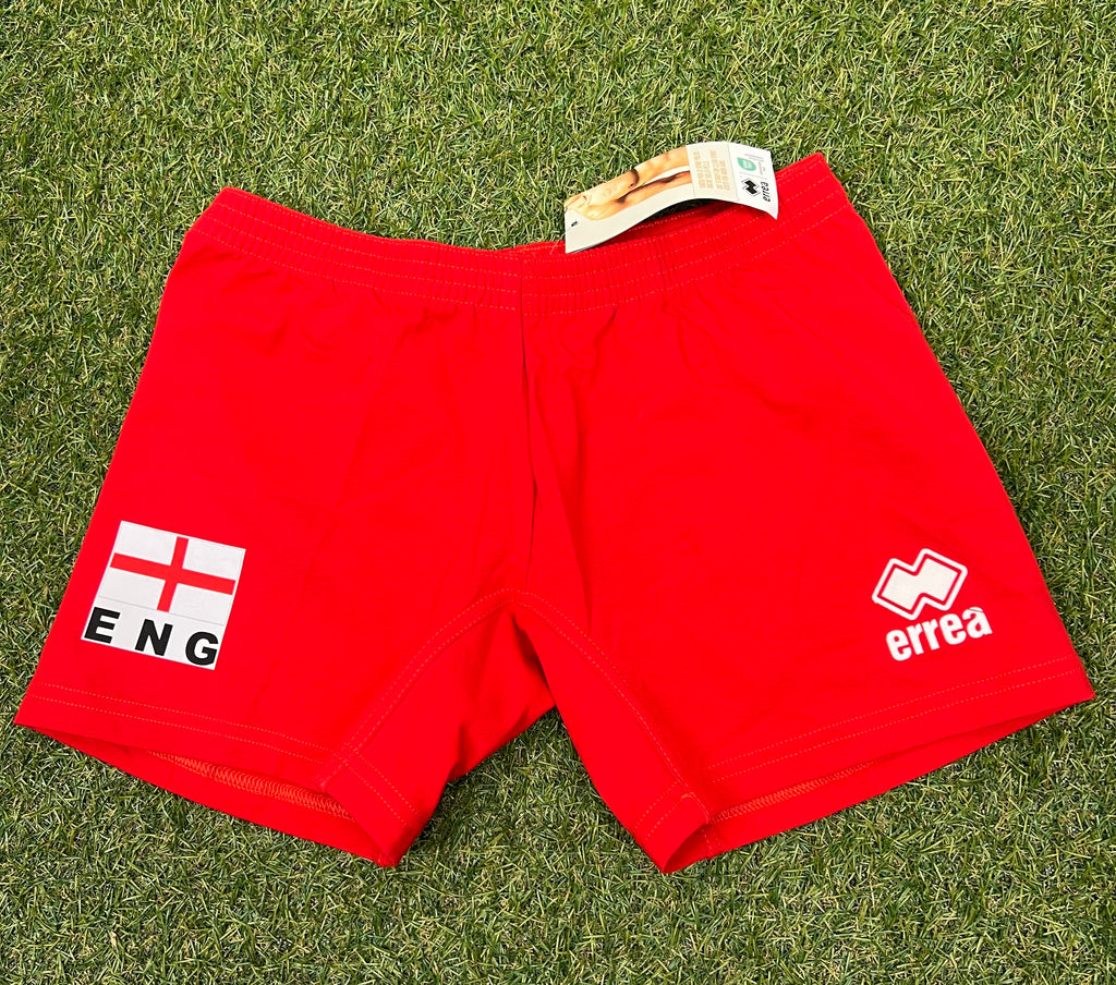 Front view of women's red volleyball shorts on grass, showing elastic waistband and England flag with 'ENG' text and Erreà logo