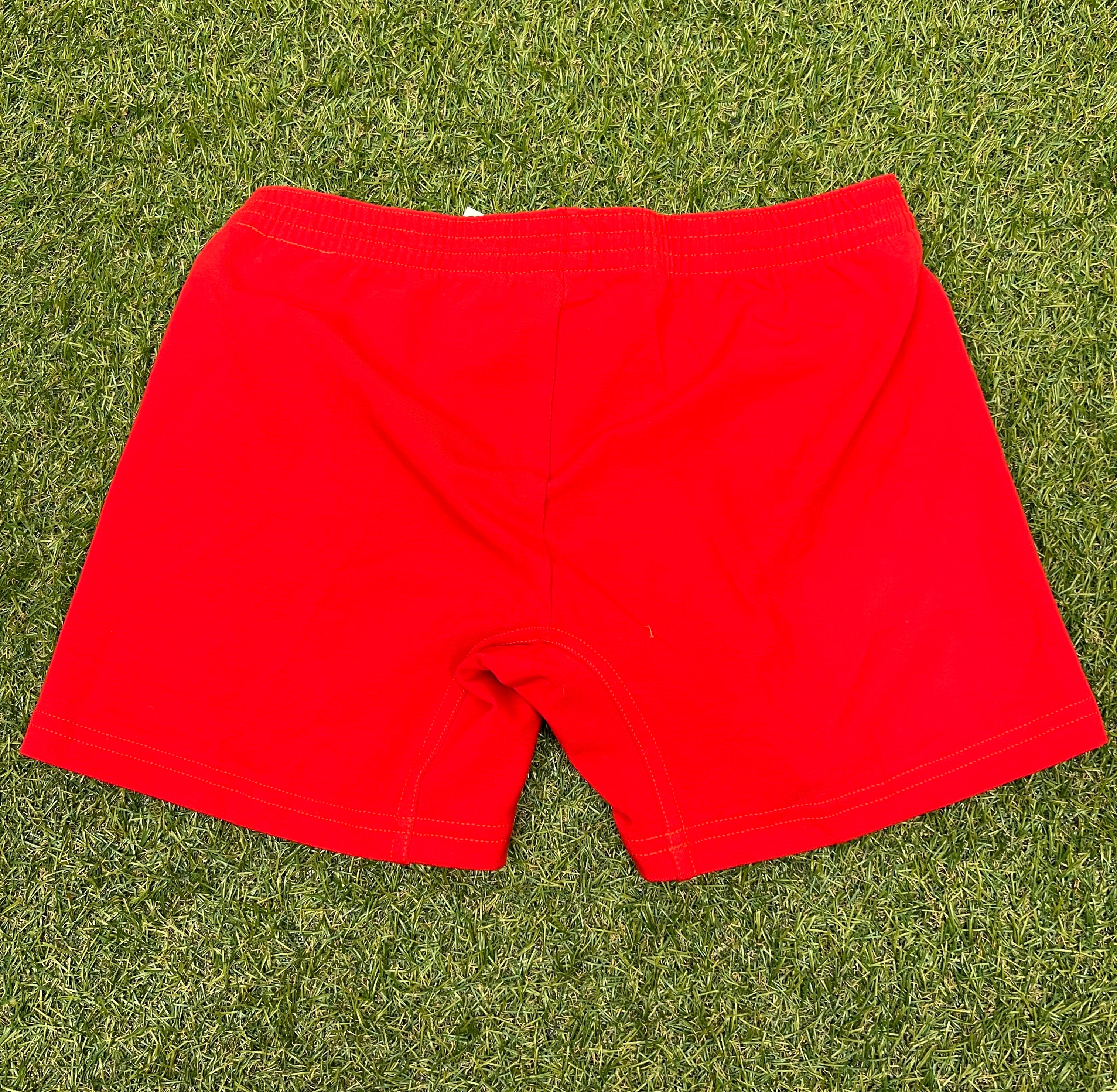 Back view of women's red volleyball shorts lying flat on grass, highlighting smooth fabric and clean stitching