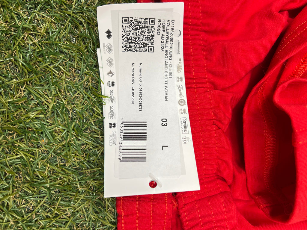 Close-up of size L tag showing product details including 'Volleyball England short woman' and barcode on red shorts