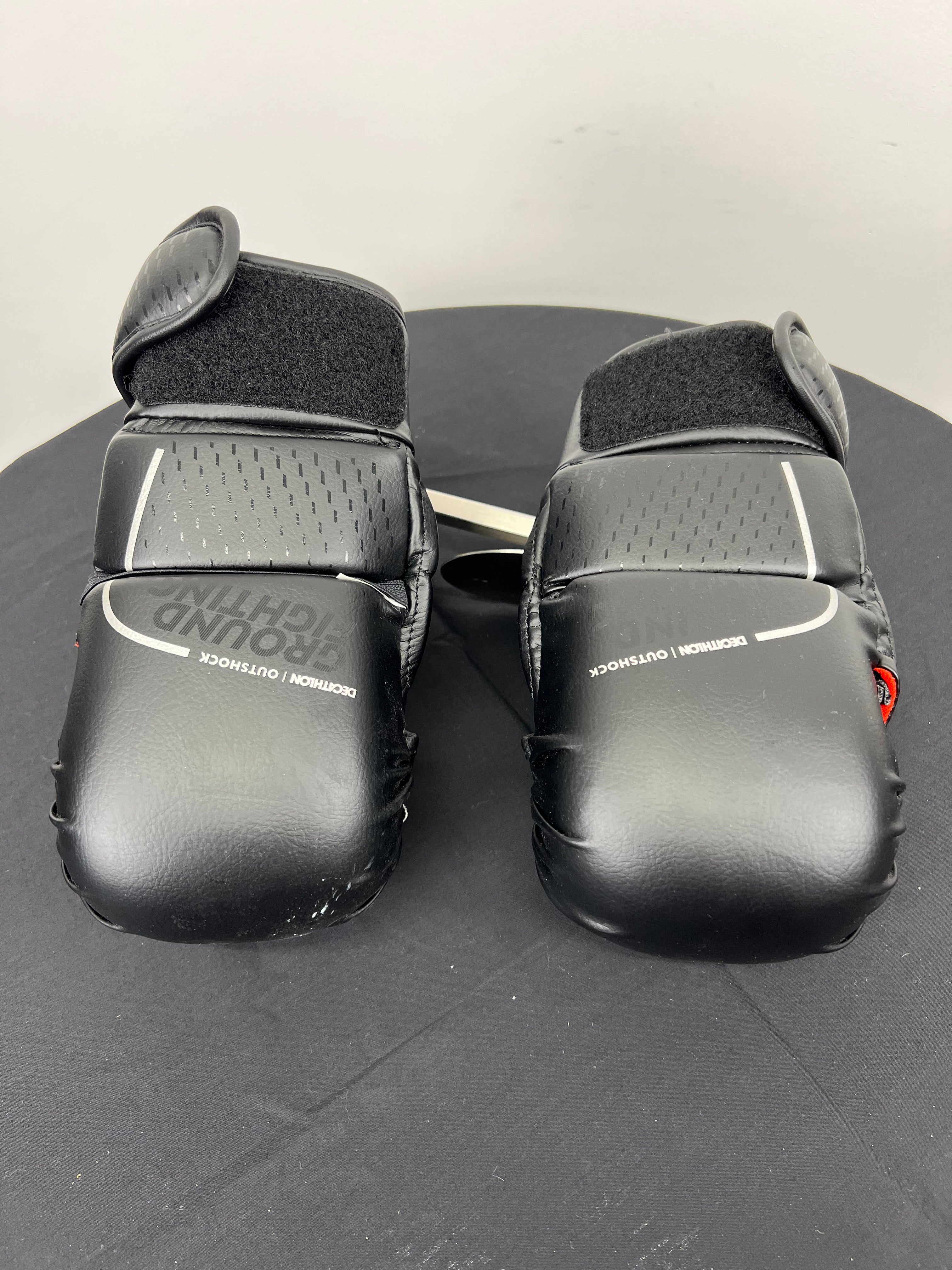 Pair of black Outshock grappling gloves with padded knuckles and Velcro wrist straps viewed from the top