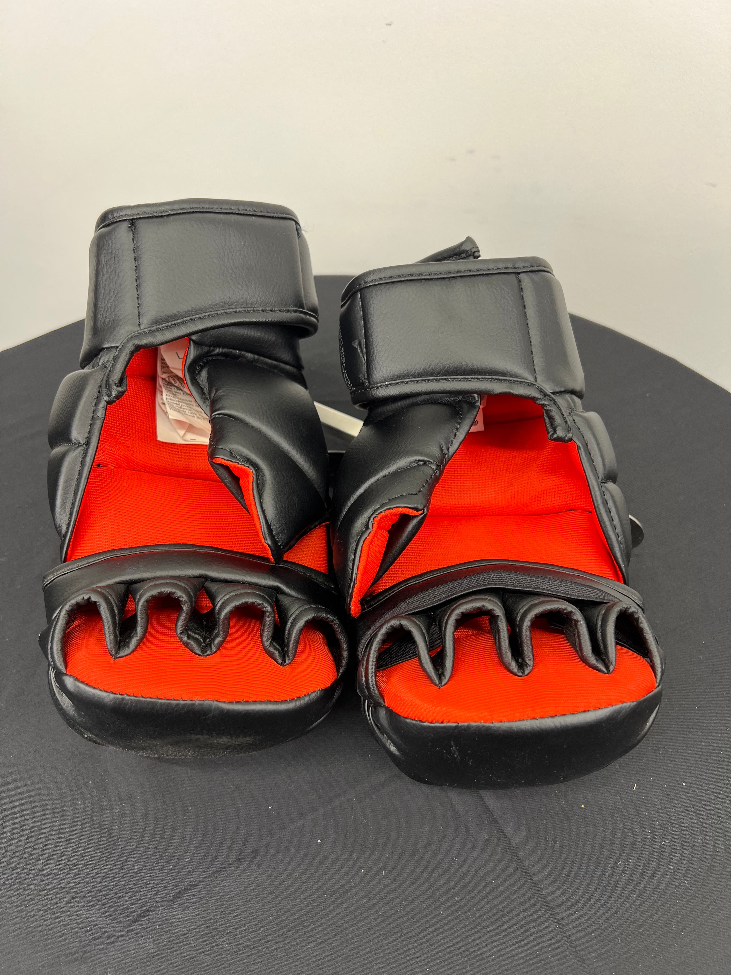 Inside view of Outshock grappling gloves showing red inner lining and open finger design with adjustable wrist straps