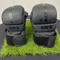Front view of Kara by RDX 7oz black grappling gloves with velvet wrist straps on artificial grass