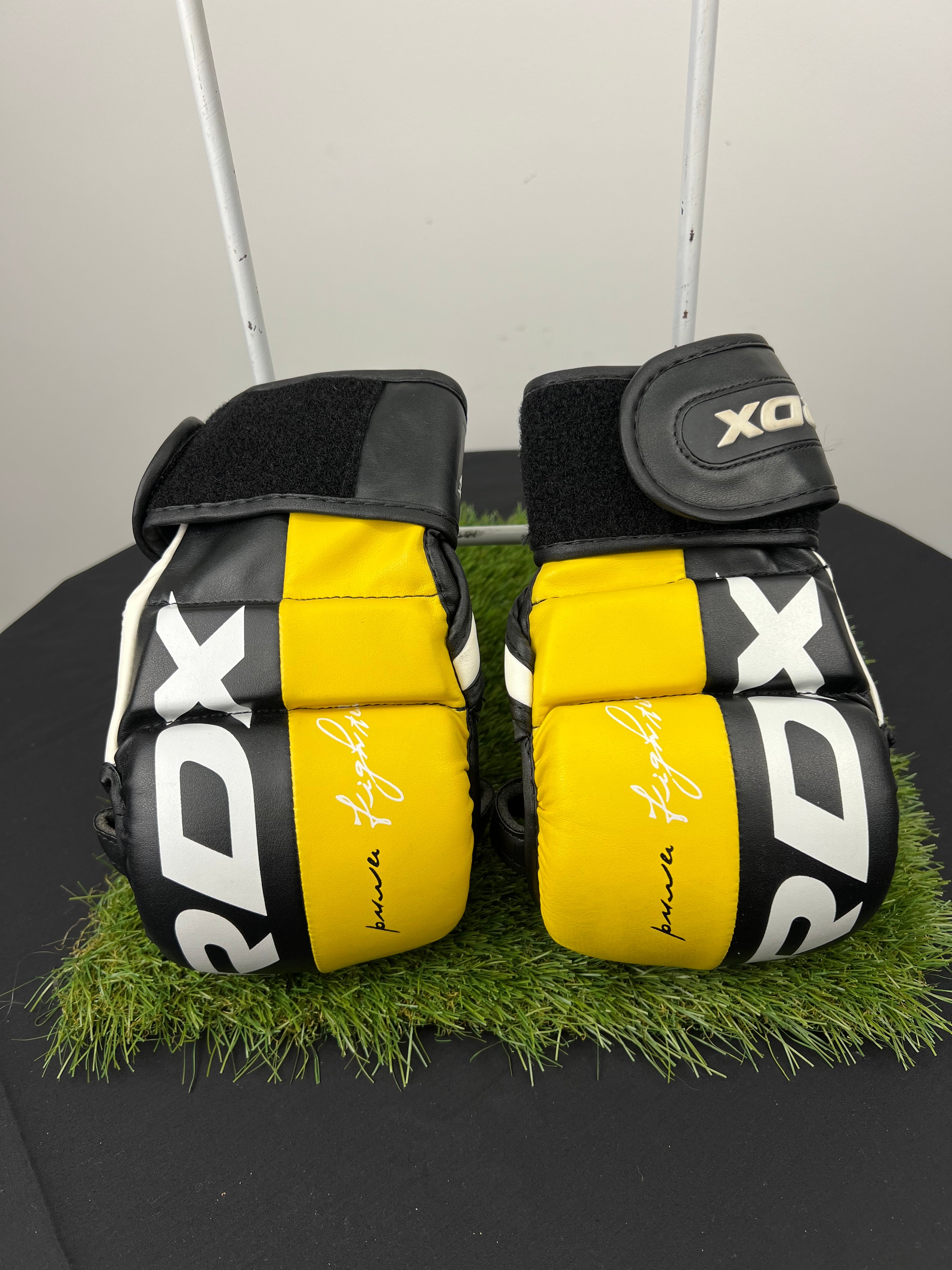 Pair of RDX T6 MMA sparring gloves in black and yellow front view showing padded knuckles and adjustable wrist strap