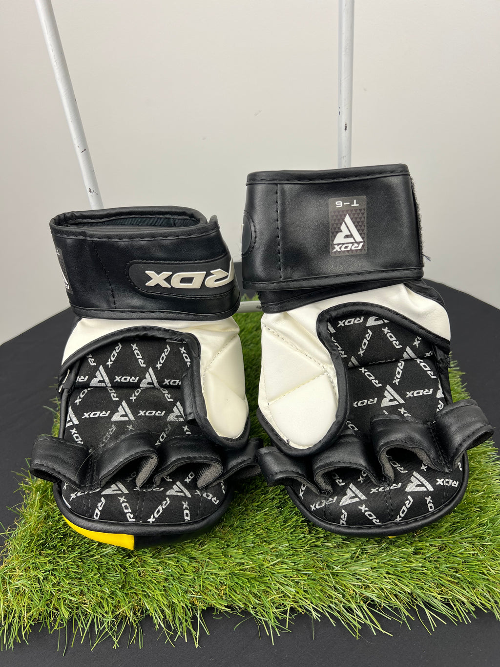 Inner side view of RDX T6 MMA sparring gloves in black and yellow showing finger openings, palm padding, and Velcro wrist strap