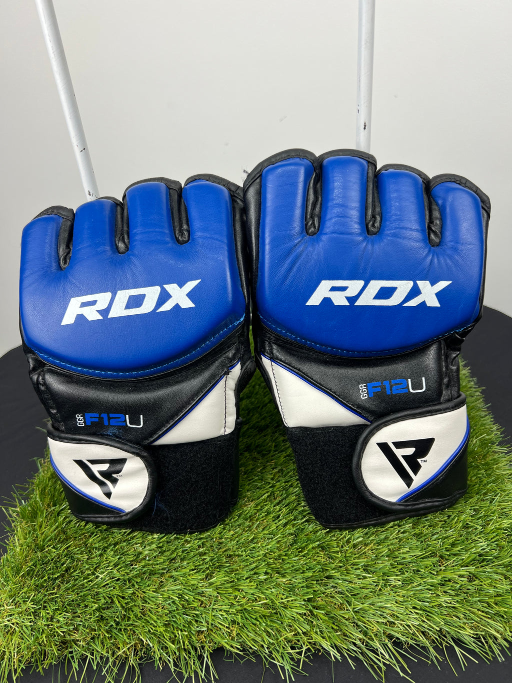 Front view of RDX F12U large grappling gloves in blue, black and white on artificial grass