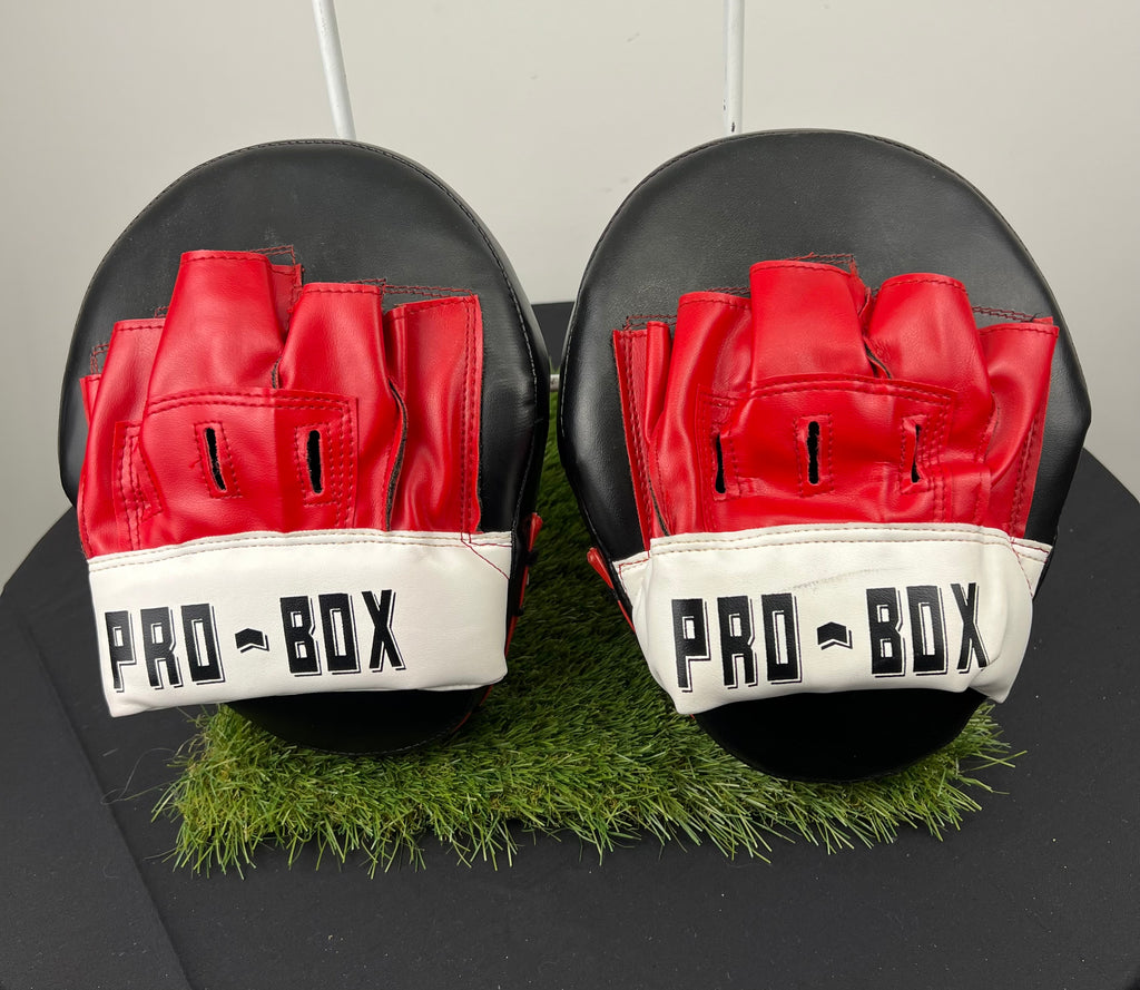 Front view of Pro-Box curved sparring pads showing red finger slots and white wrist strap with Pro-Box logo
