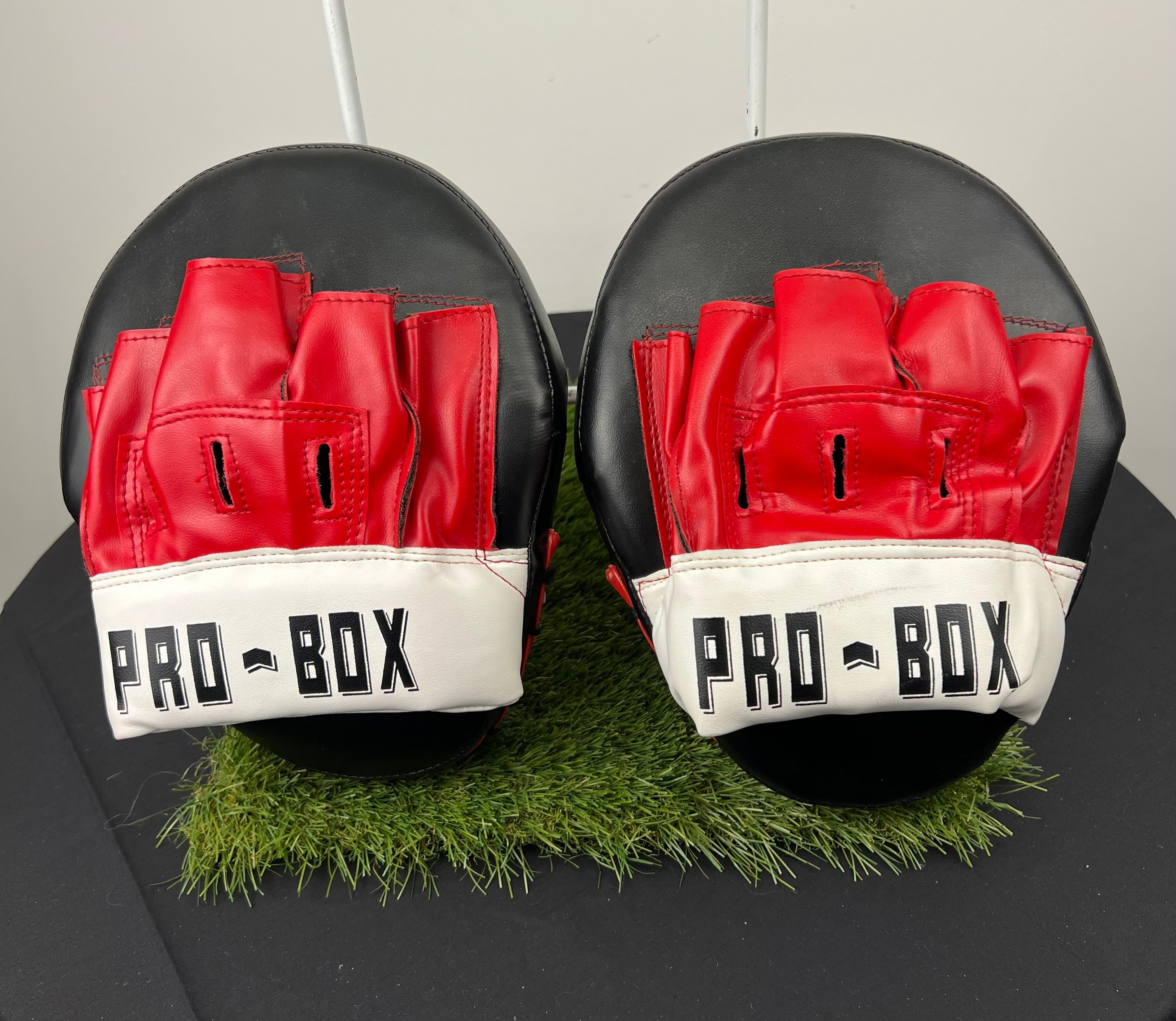 Front view of Pro-Box curved sparring pads showing red finger slots and white wrist strap with Pro-Box logo
