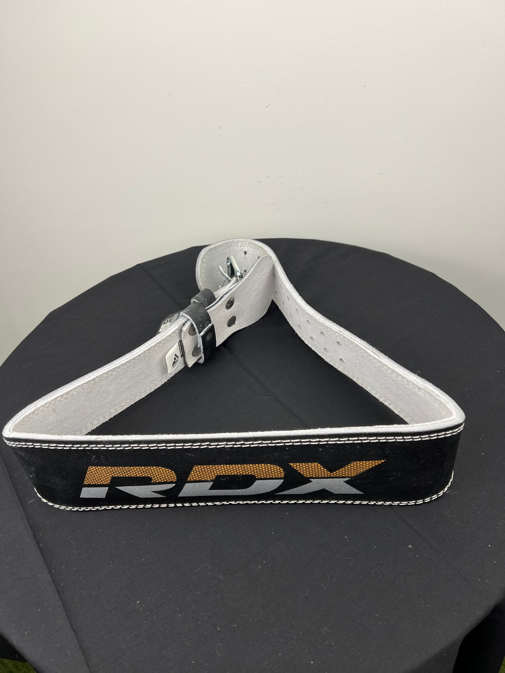 RDX 4 inch leather weightlifting belt laid out showing inside surface and metal buckle