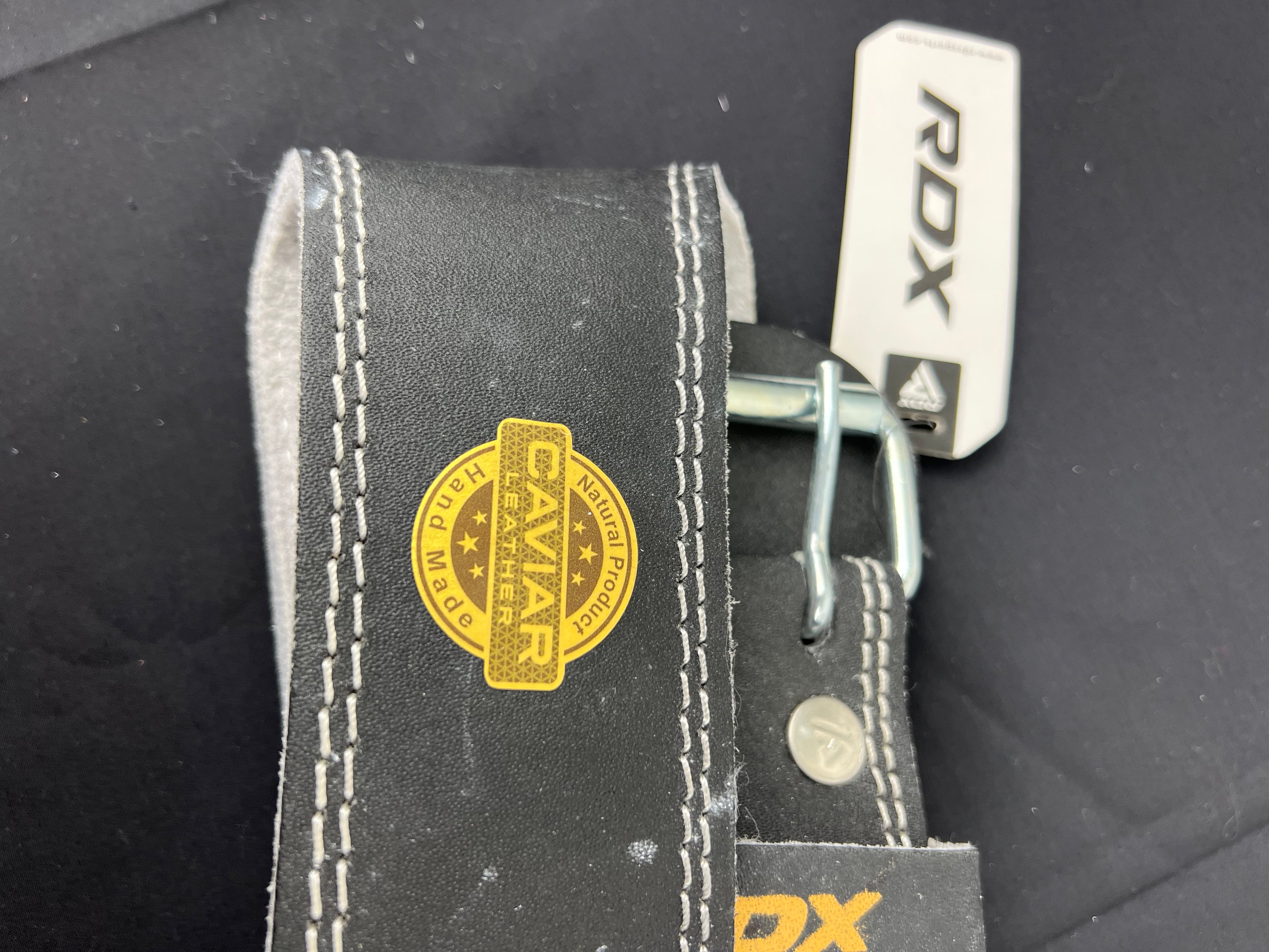 Metal buckle of RDX weightlifting belt with caviar leather label and XL size tag