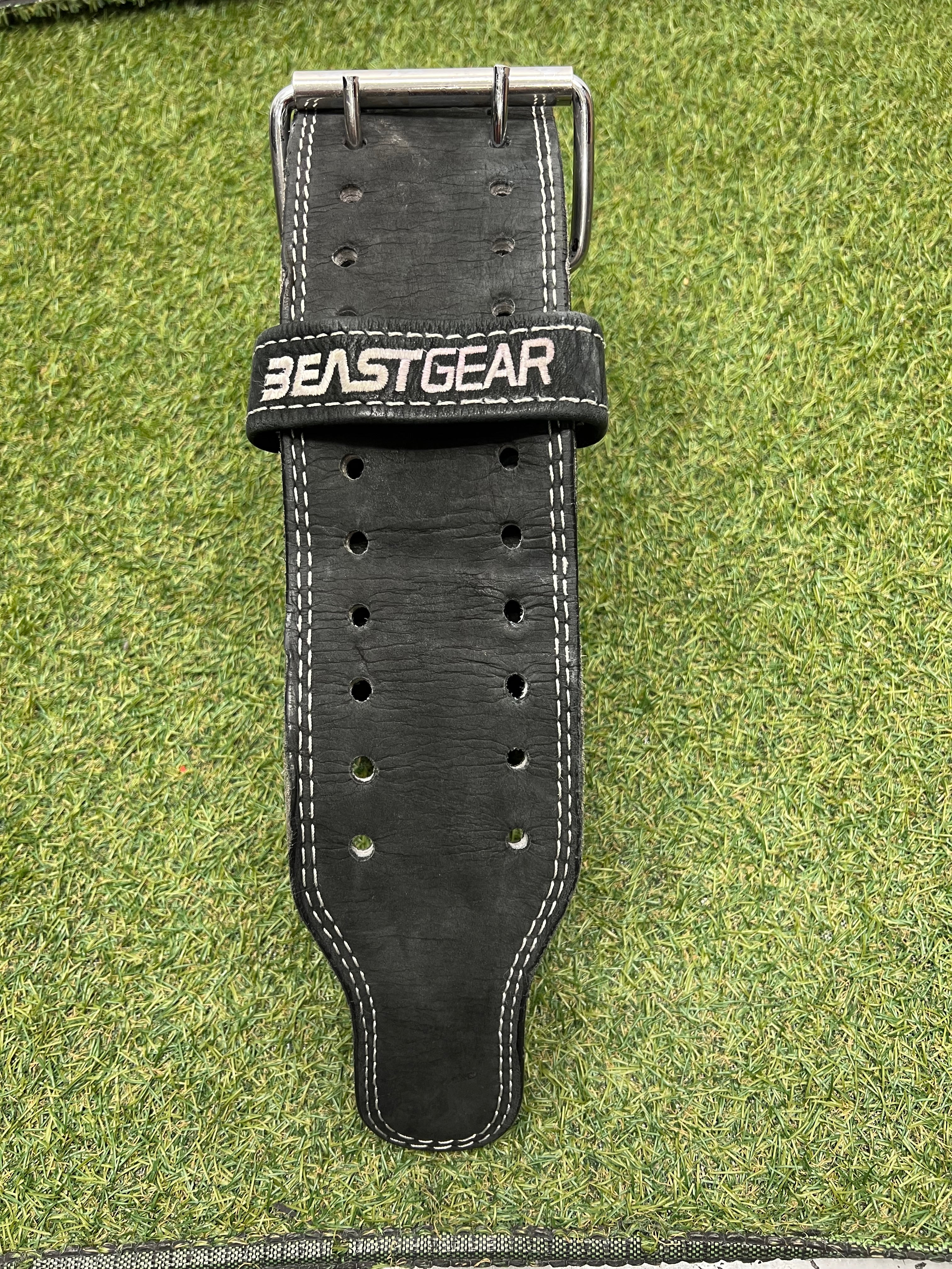 Close-up of the belt buckle and multiple adjustment holes on black leather weightlifting belt with Beast Gear branding