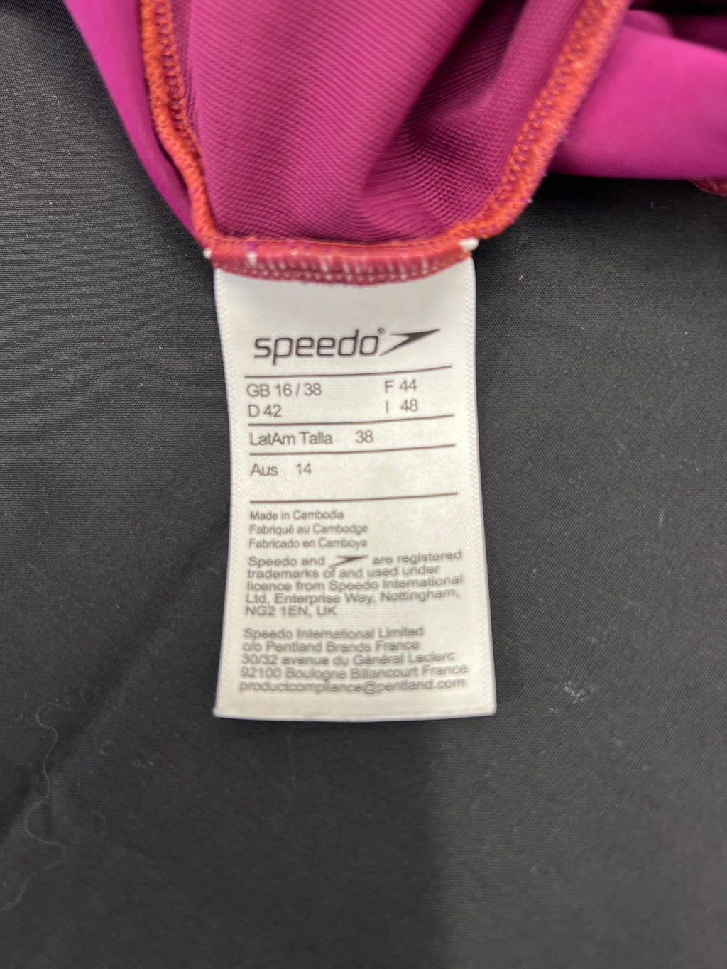 Close-up of inside size label of purple Speedo swimsuit showing size details and origin