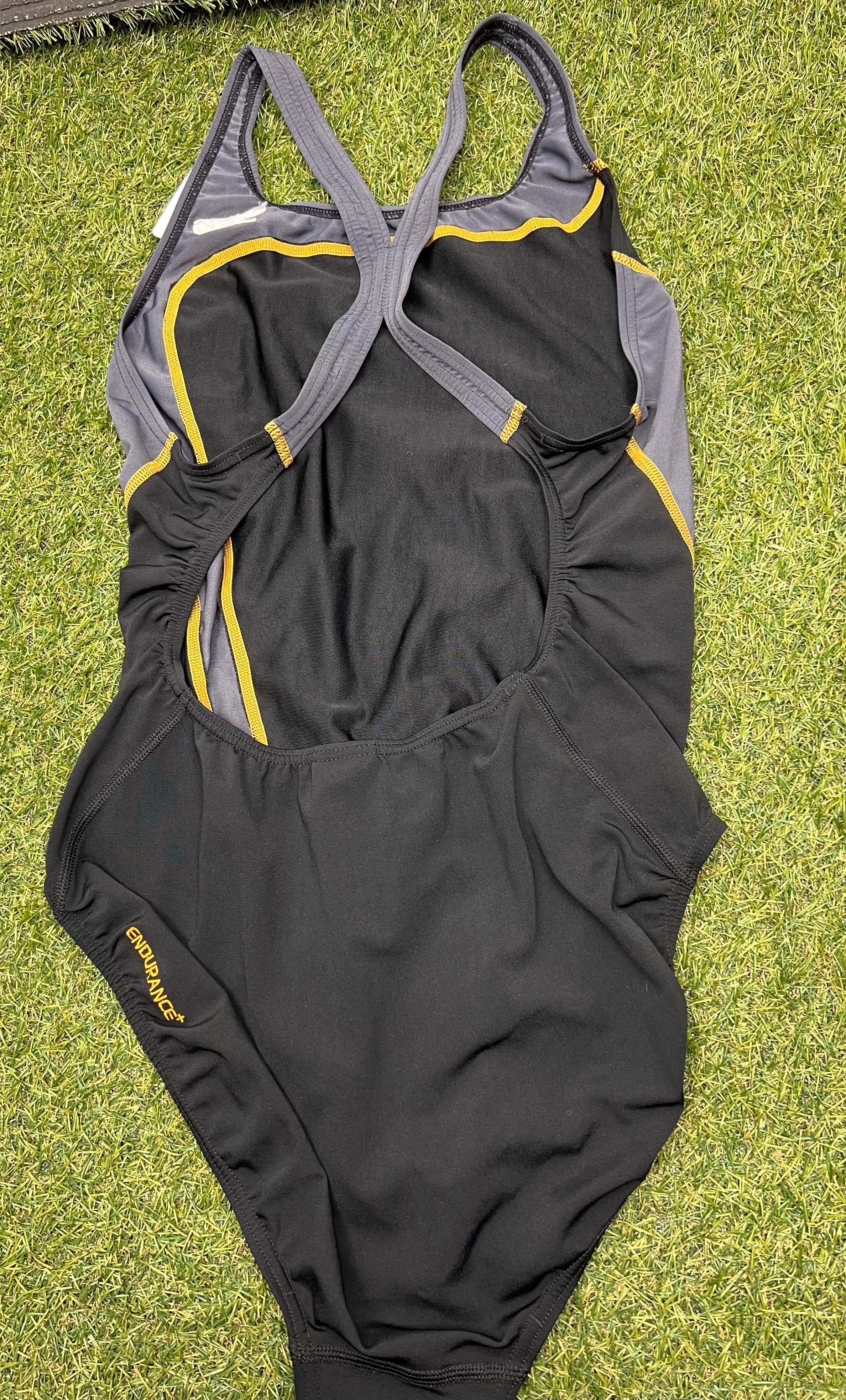 Back view of Speedo women's black and grey swimsuit showing crossed straps and Endurance+ logo