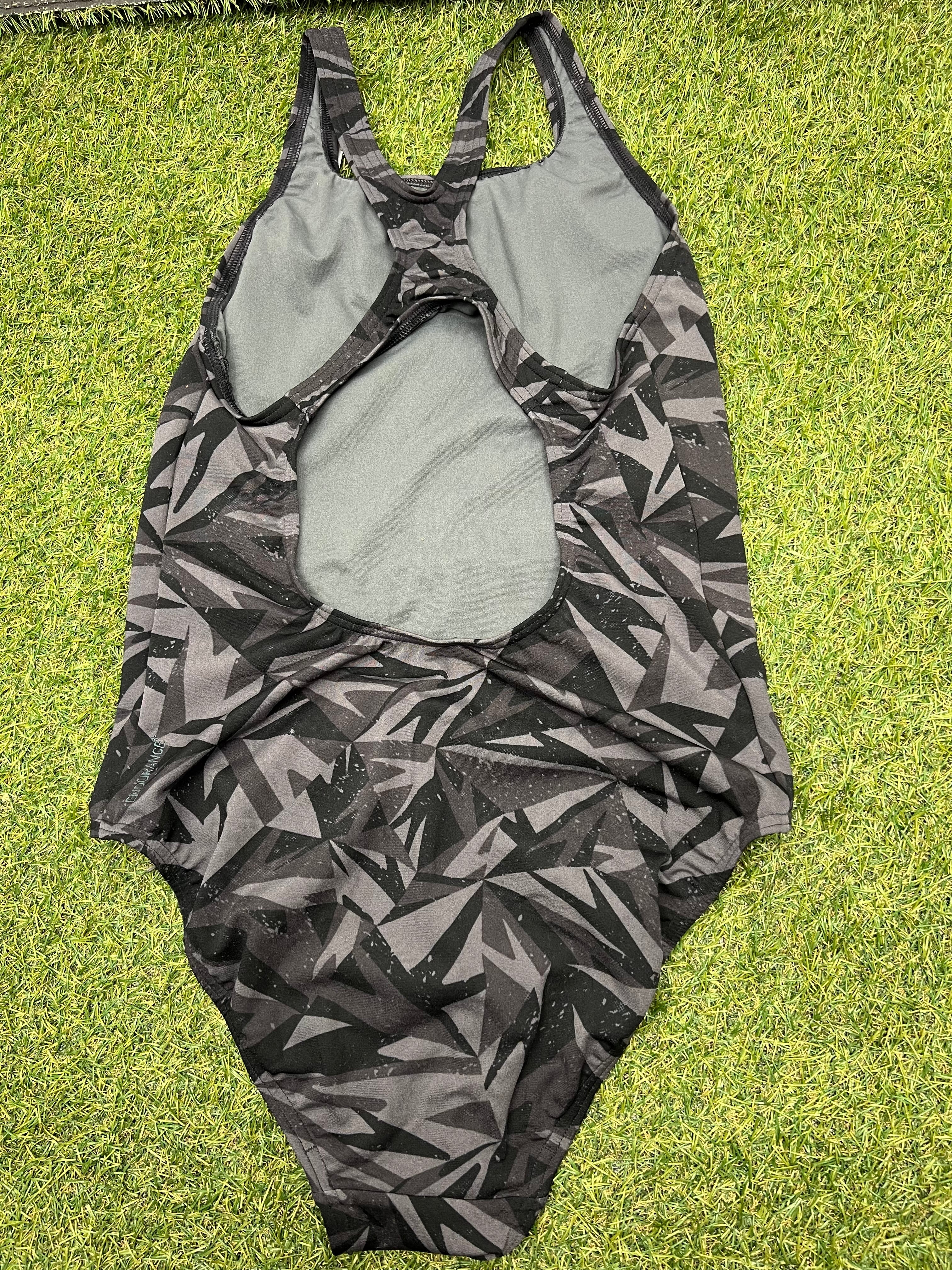 Back view of women's Speedo swimsuit showing racerback and keyhole detail on grass