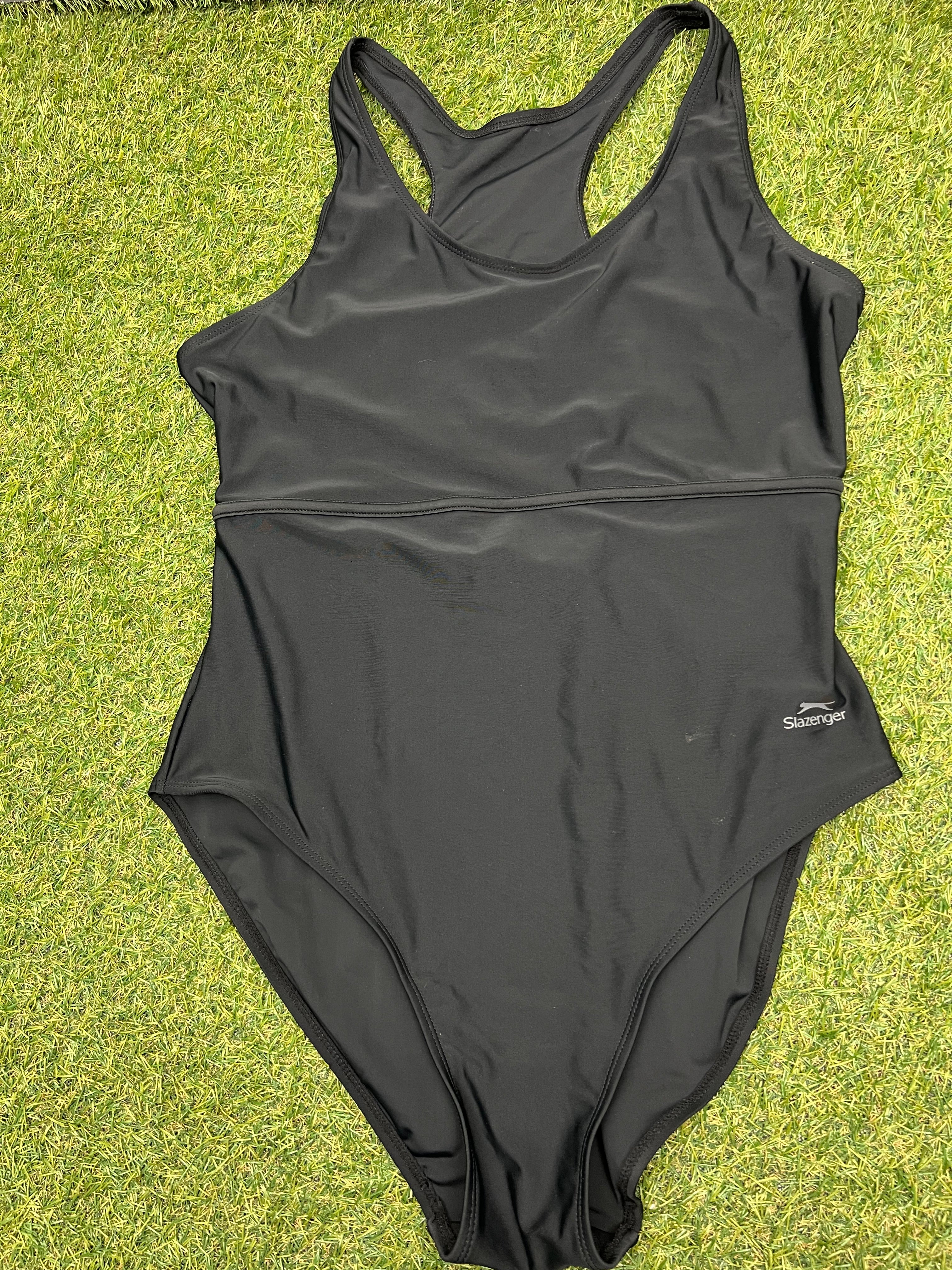 Front view of women’s black Slazenger one-piece swimsuit size 16 laid on grass