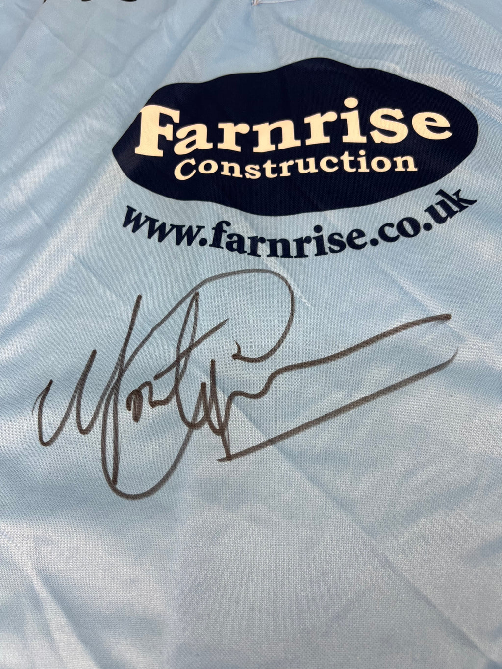 Close-up of Monty Panesar's autograph on the front of the Sussex Sharks cricket shirt near the Farnrise Construction logo
