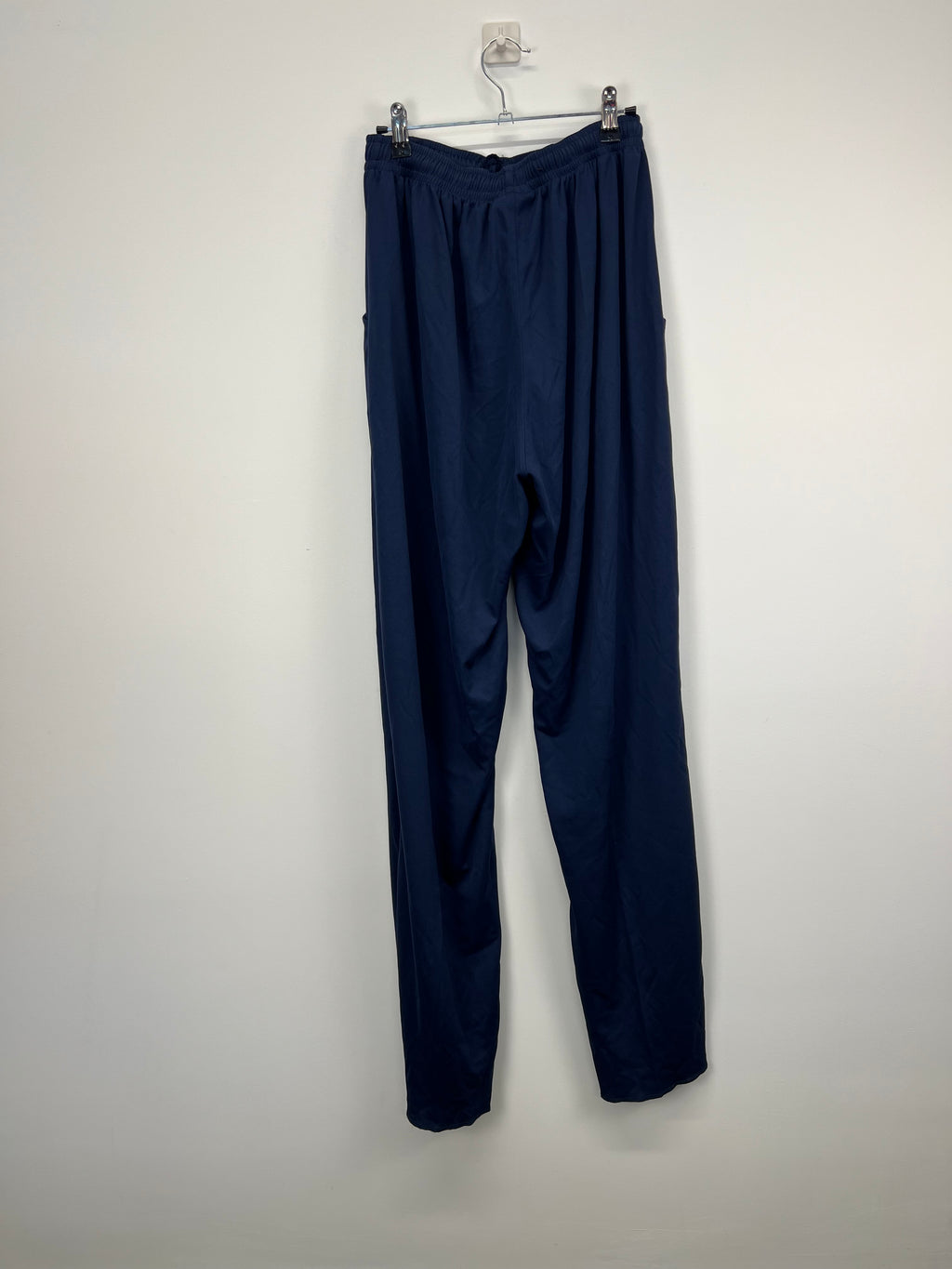 Rear view of the navy blue men’s Surridge cricket bottoms hanging on a hanger showing their clean and simple design