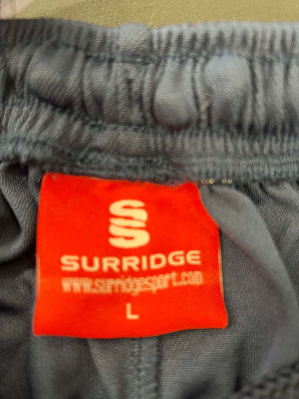 Close-up of the Surridge red label with size L on the inner waistband of the cricket bottoms