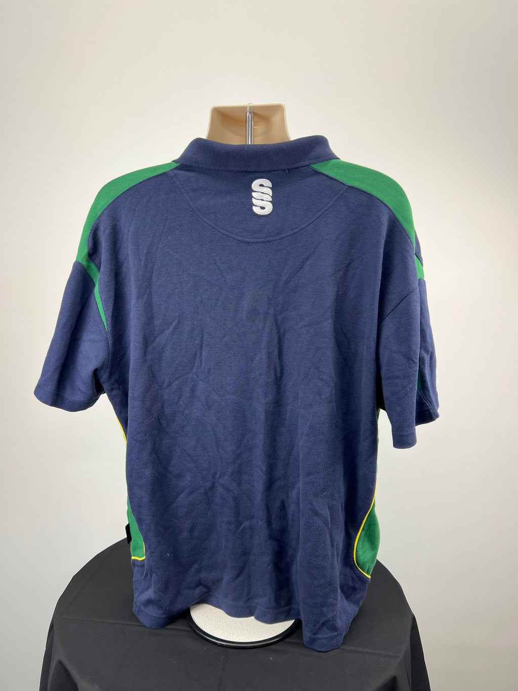 Back view of navy Northants cricket polo showing green accents and Suridge logo on the collar