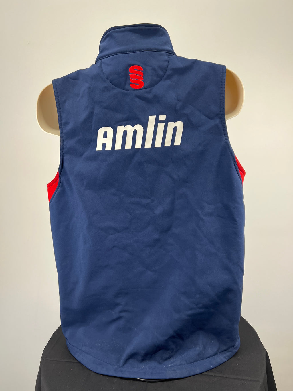 Back view of navy blue cricket gilet with red Surridge logo and white Amlin sponsor print