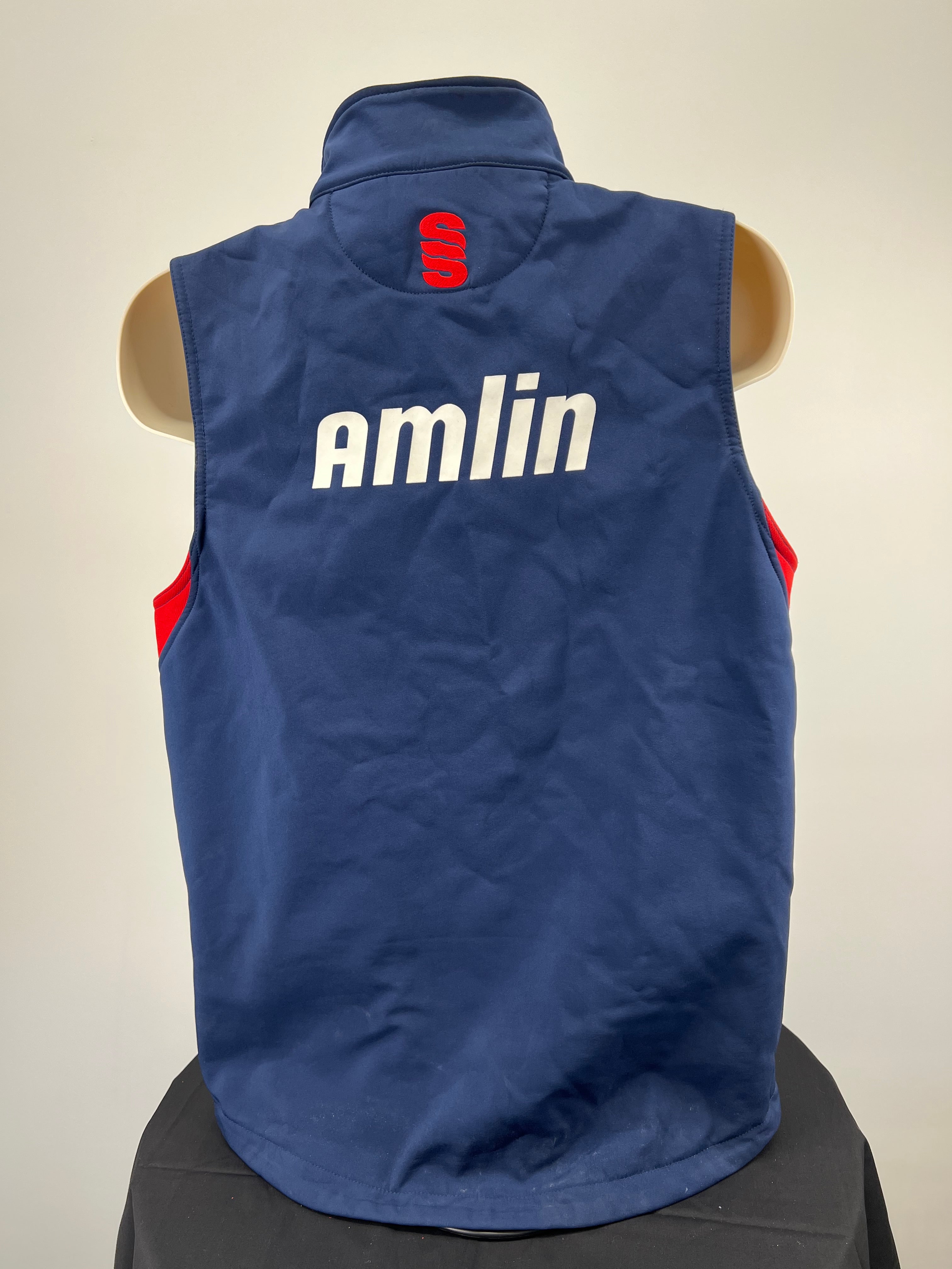 Back view of navy blue cricket gilet with red Surridge logo and white Amlin sponsor print