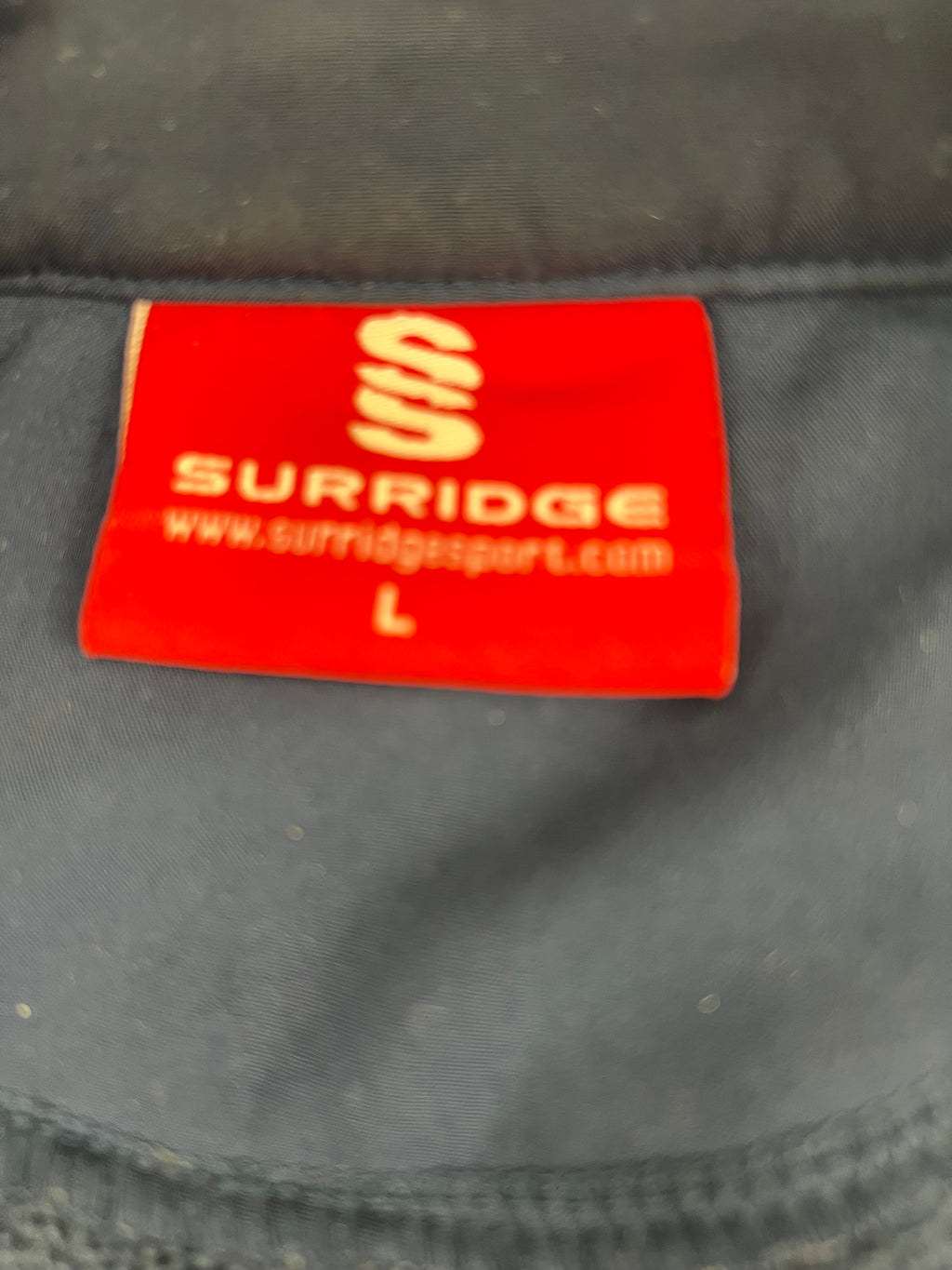 Close-up of red Surridge brand label showing size L inside cricket gilet