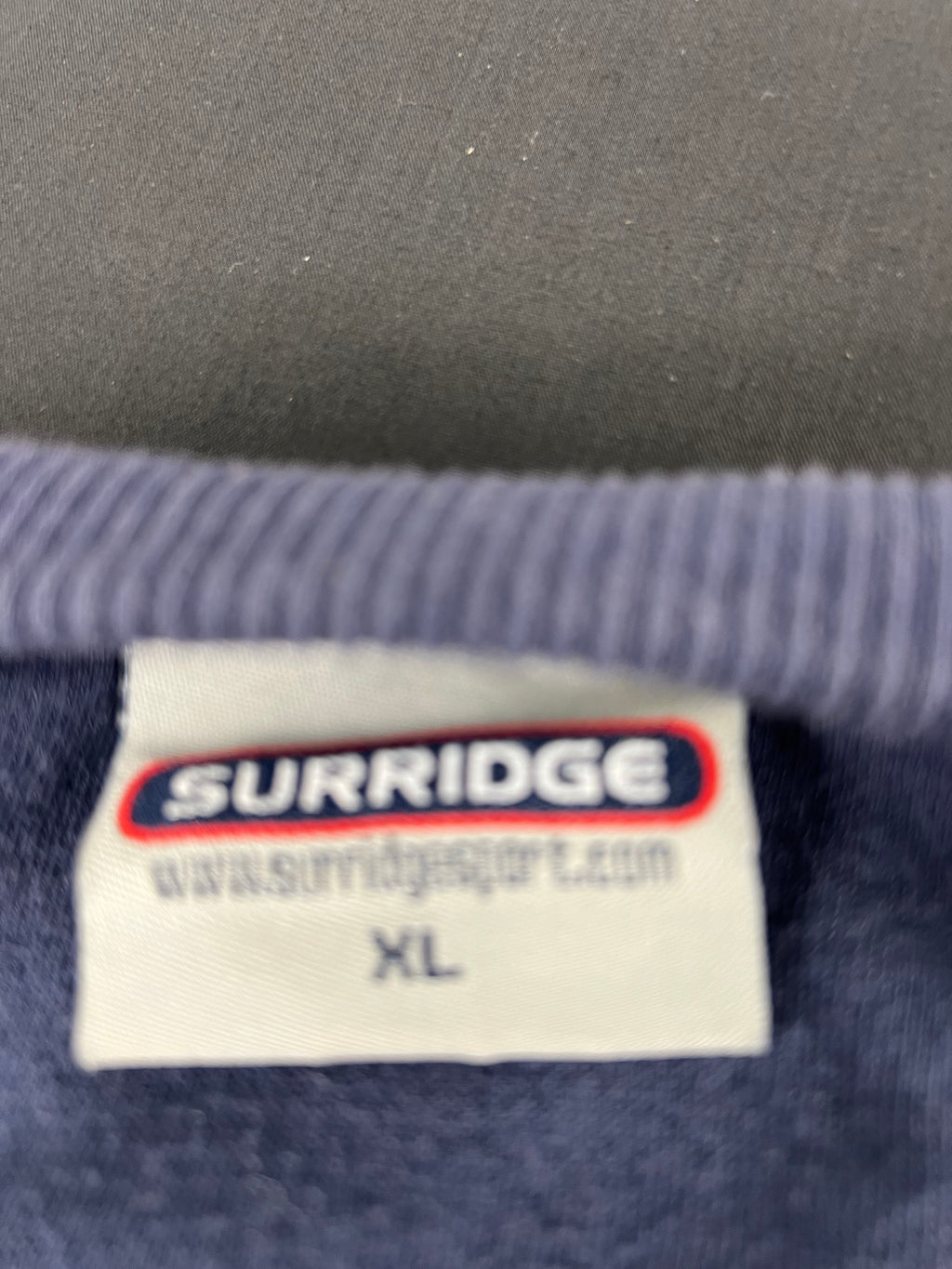 Close-up of Surridge brand label showing size XL on Northants cricket sweatshirt