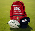 The Lions red backpack, navy cap, and white 3C Partners rugby ball together